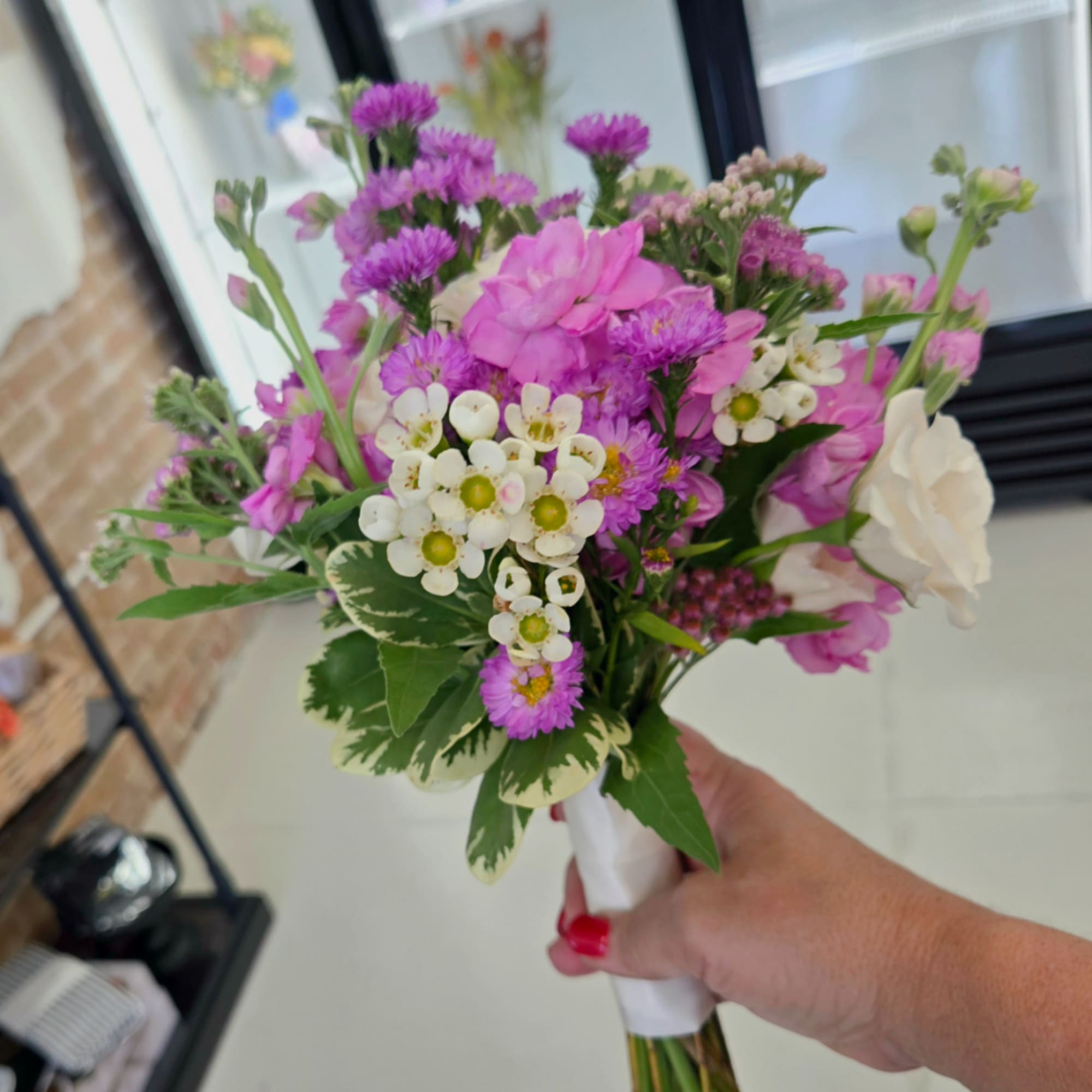 Handheld bouquet of pink and purple flowers with white blooms