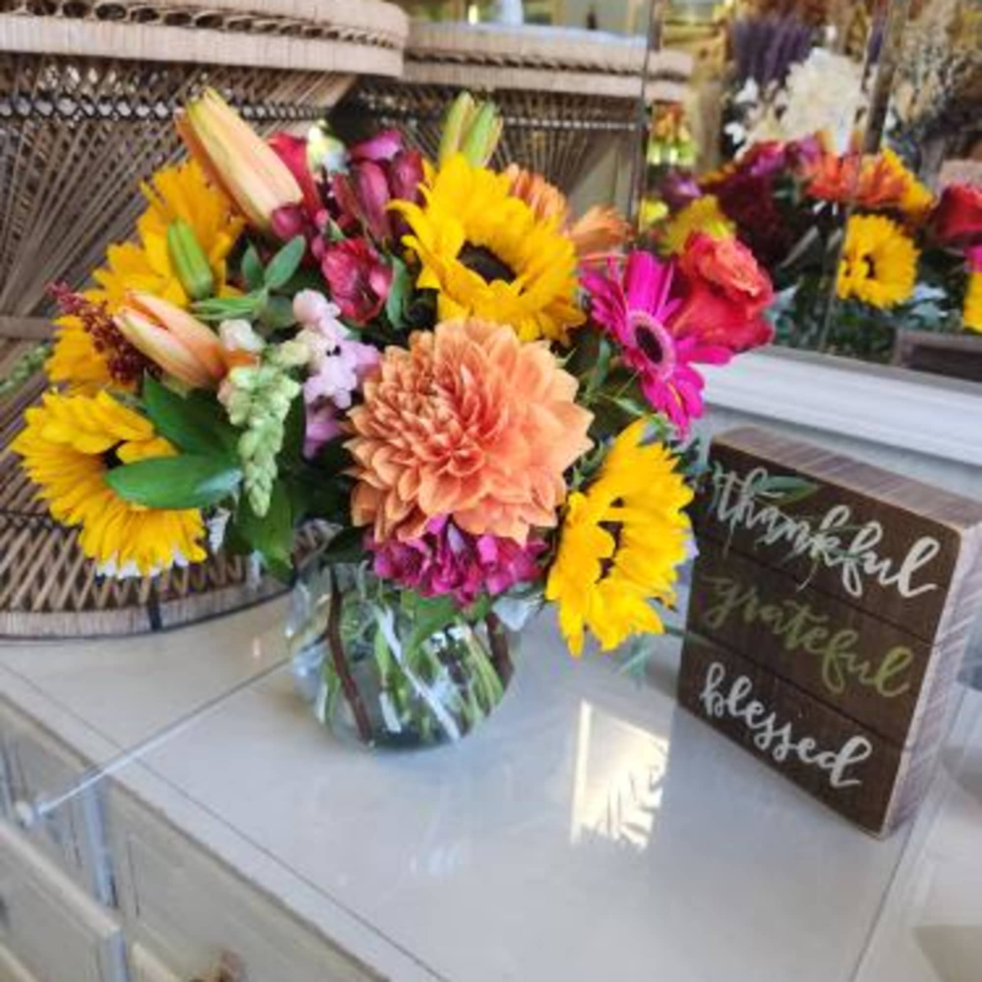 Bright mixed bouquet with sunflowers, lilies, and gerbera daisies in a glass vase