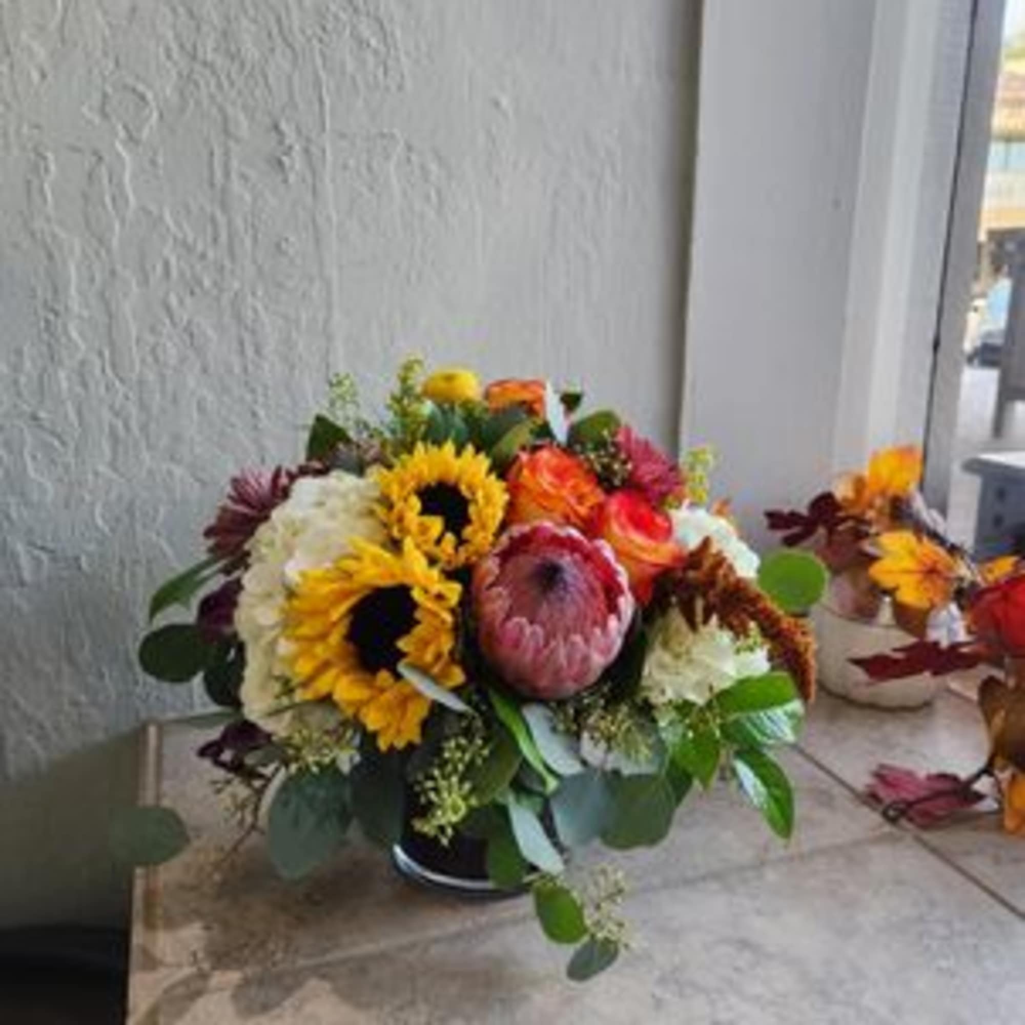 Mixed bouquet with sunflowers, protea, and white blooms in a low vase