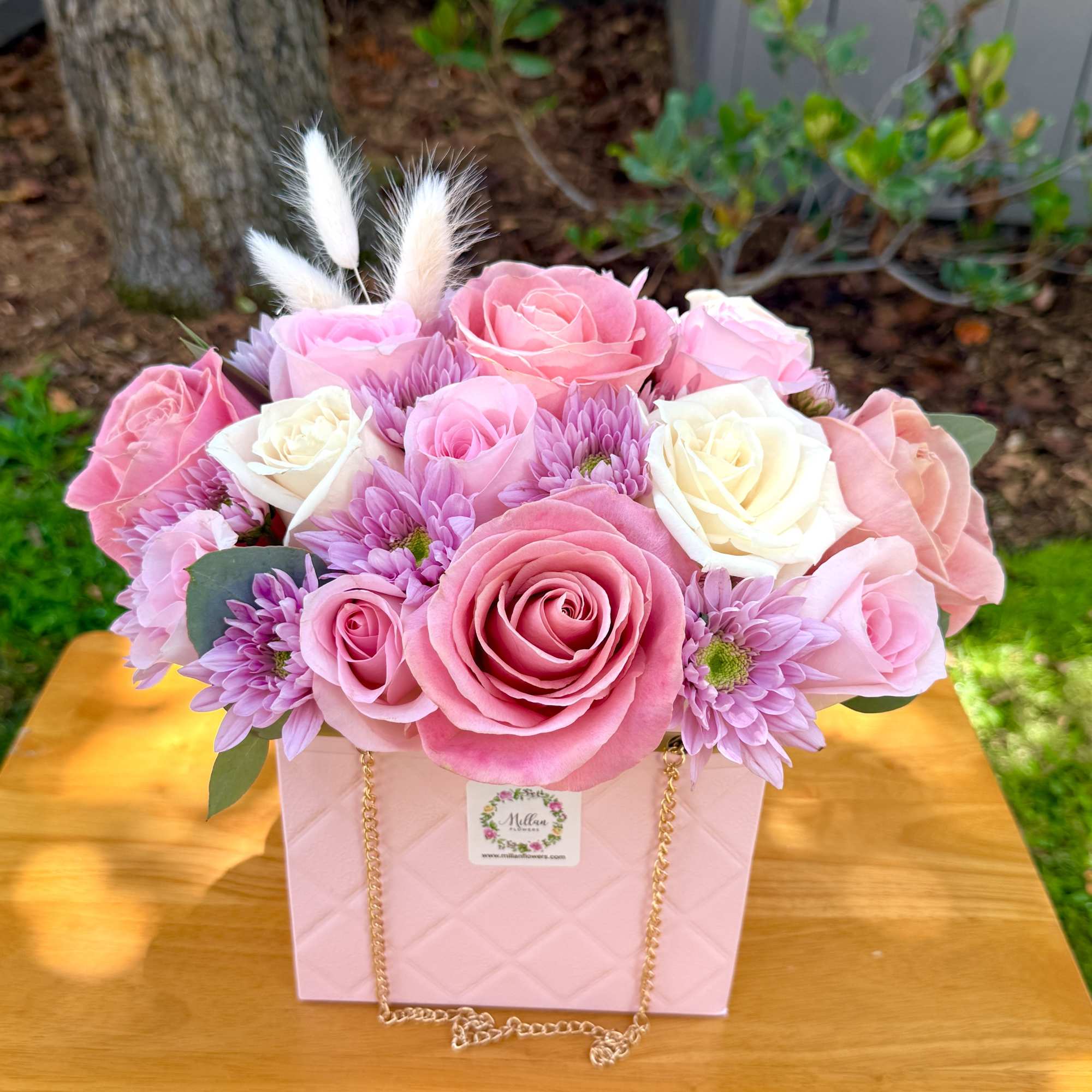 Pink and white roses with lavender blooms in a pink gift box