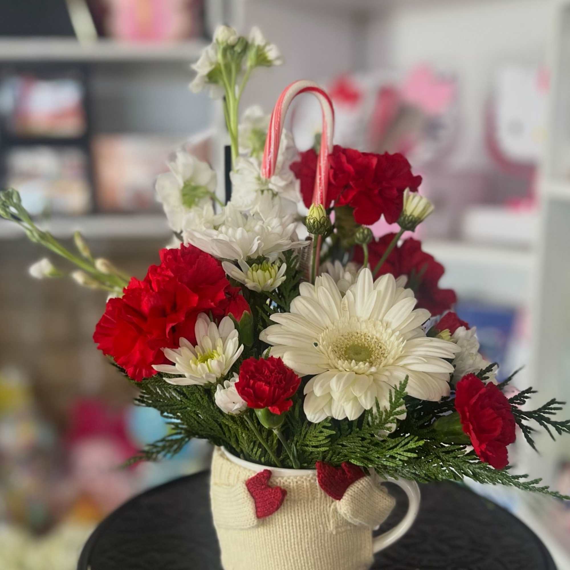 Red and white flowers arranged in a mug with a candy cane handle