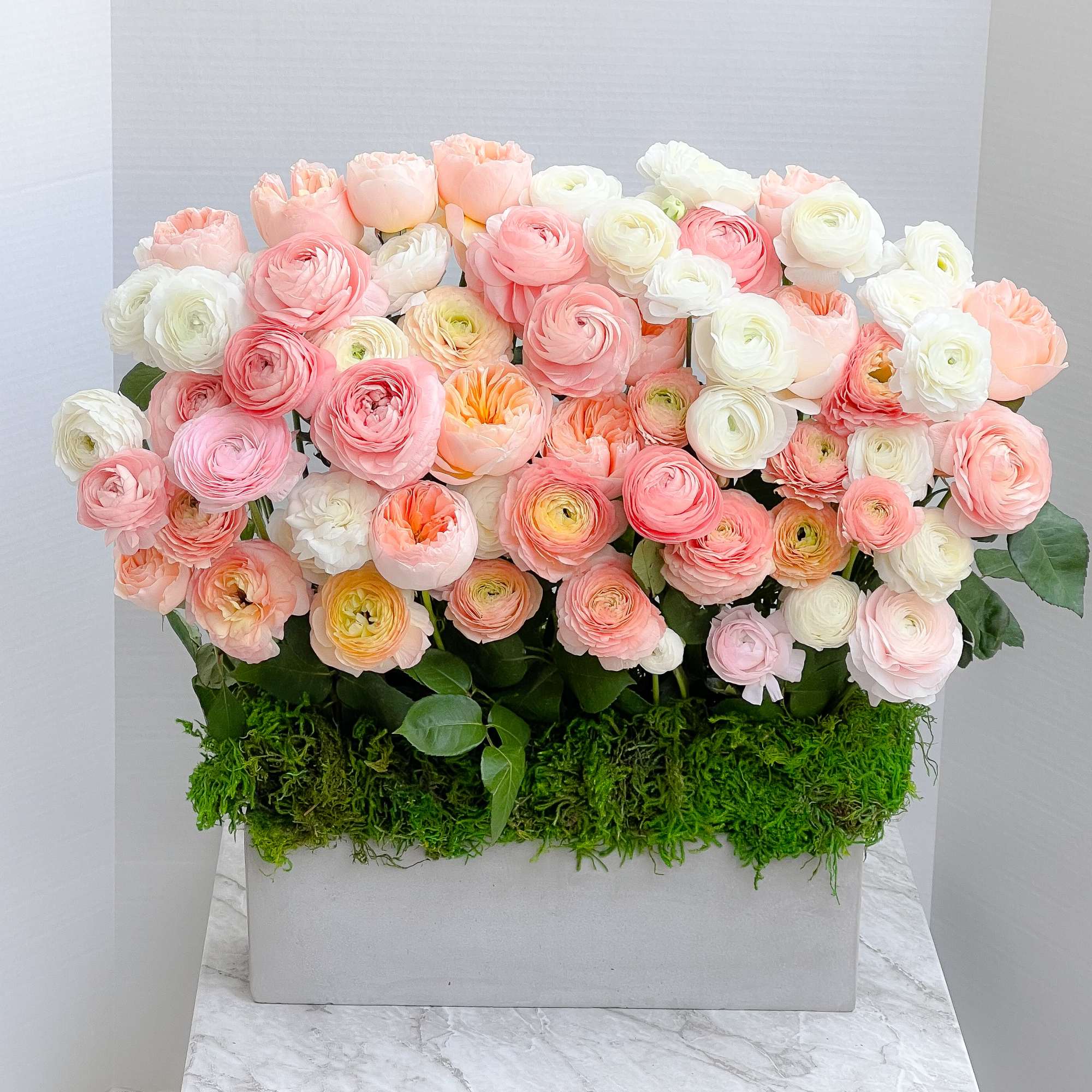 Box arrangement of pink, peach, and white ranunculus flowers