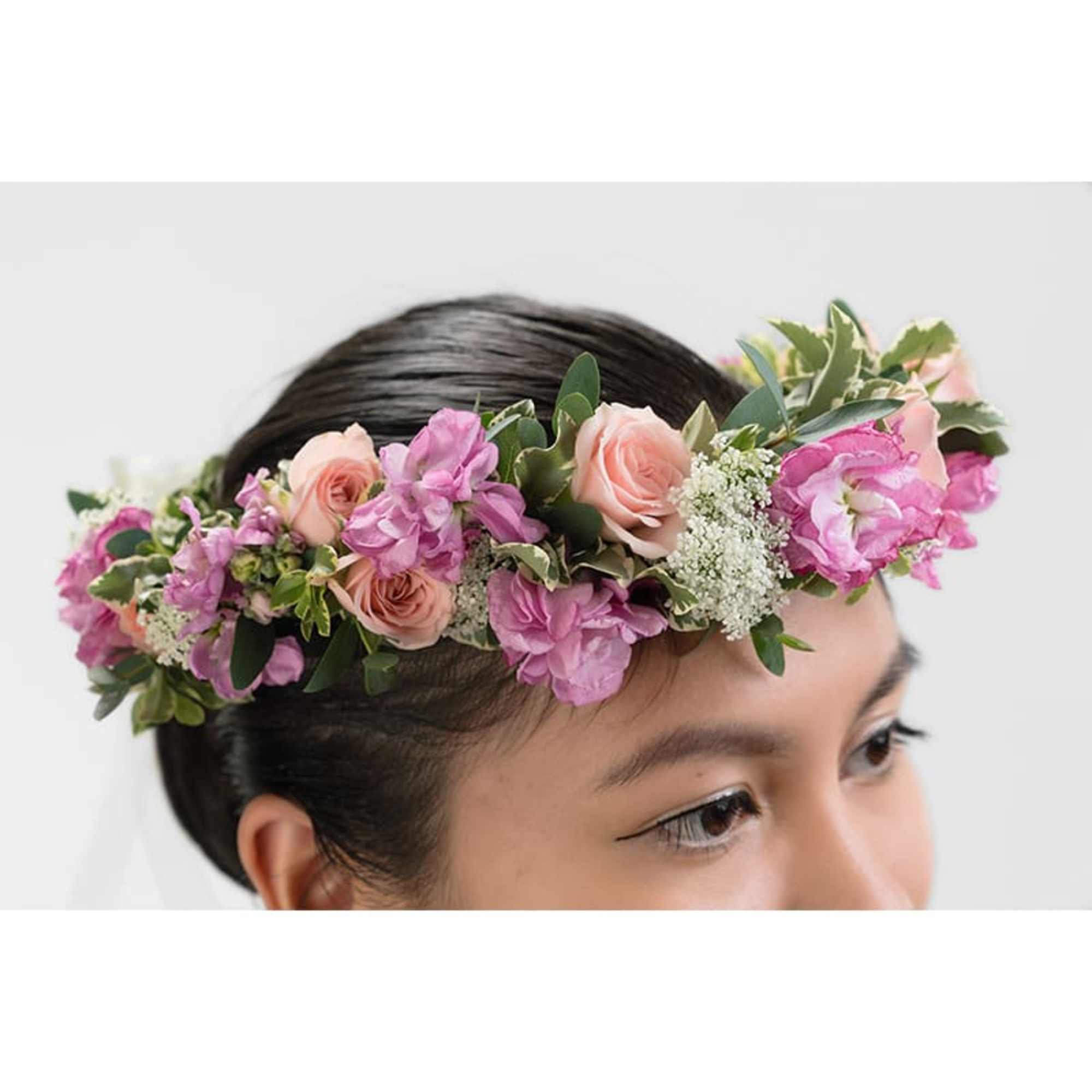 Flower crown of pink roses and purple blossoms worn on a woman's head