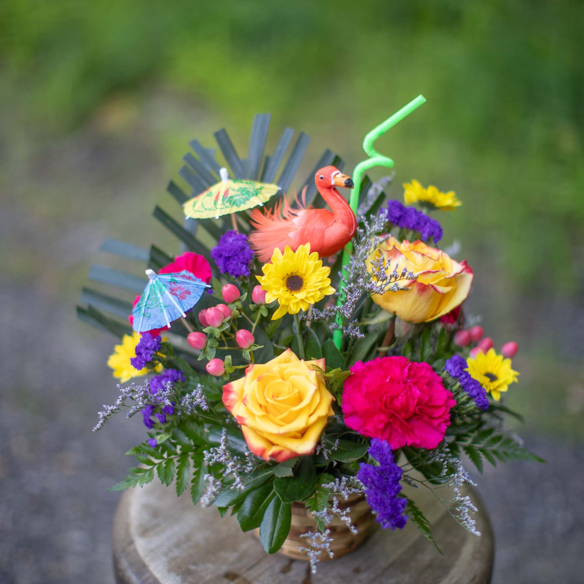 Bright mixed bouquet with roses, carnations, and a flamingo topper