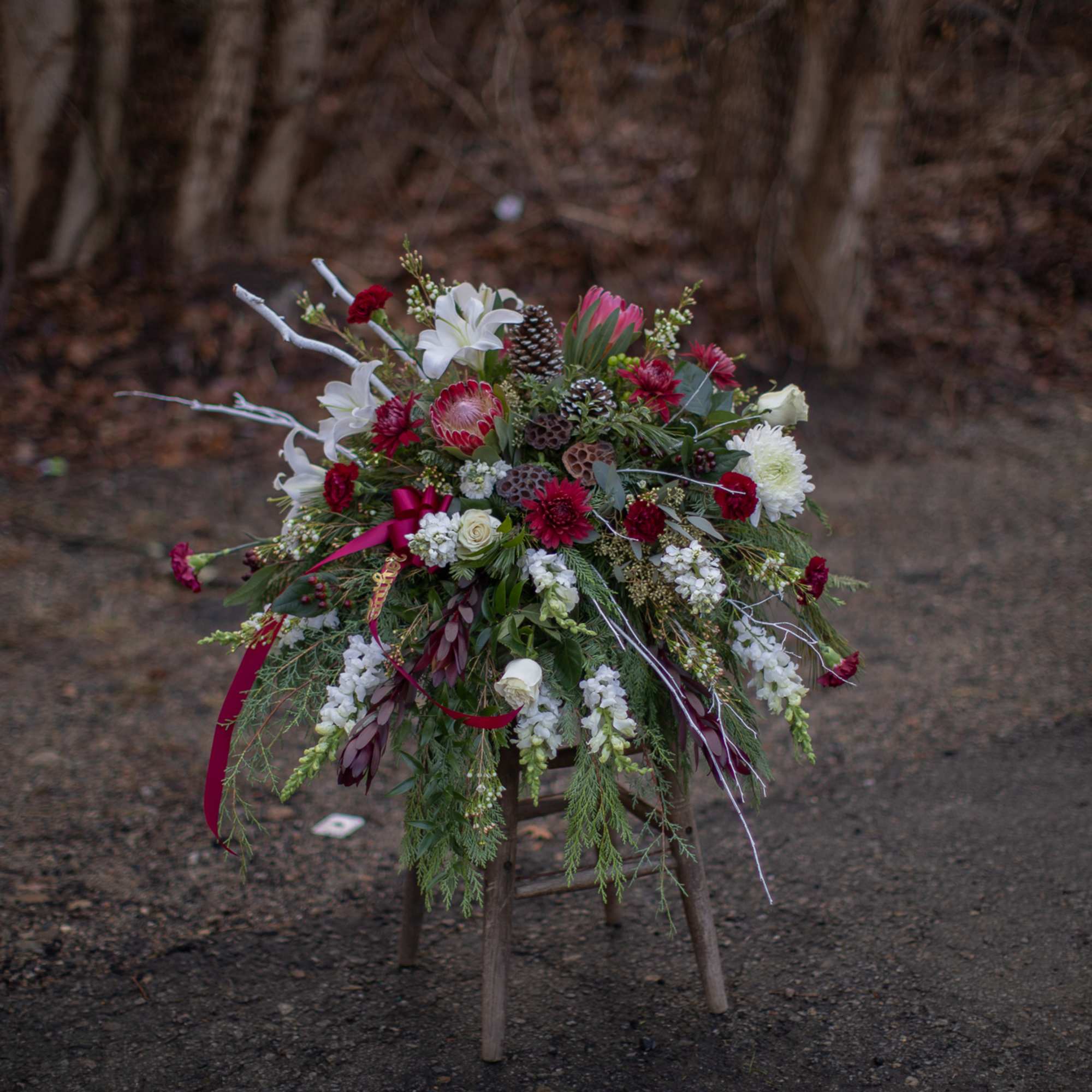 Large floral arrangement with red, white, and pink blooms on a stool
