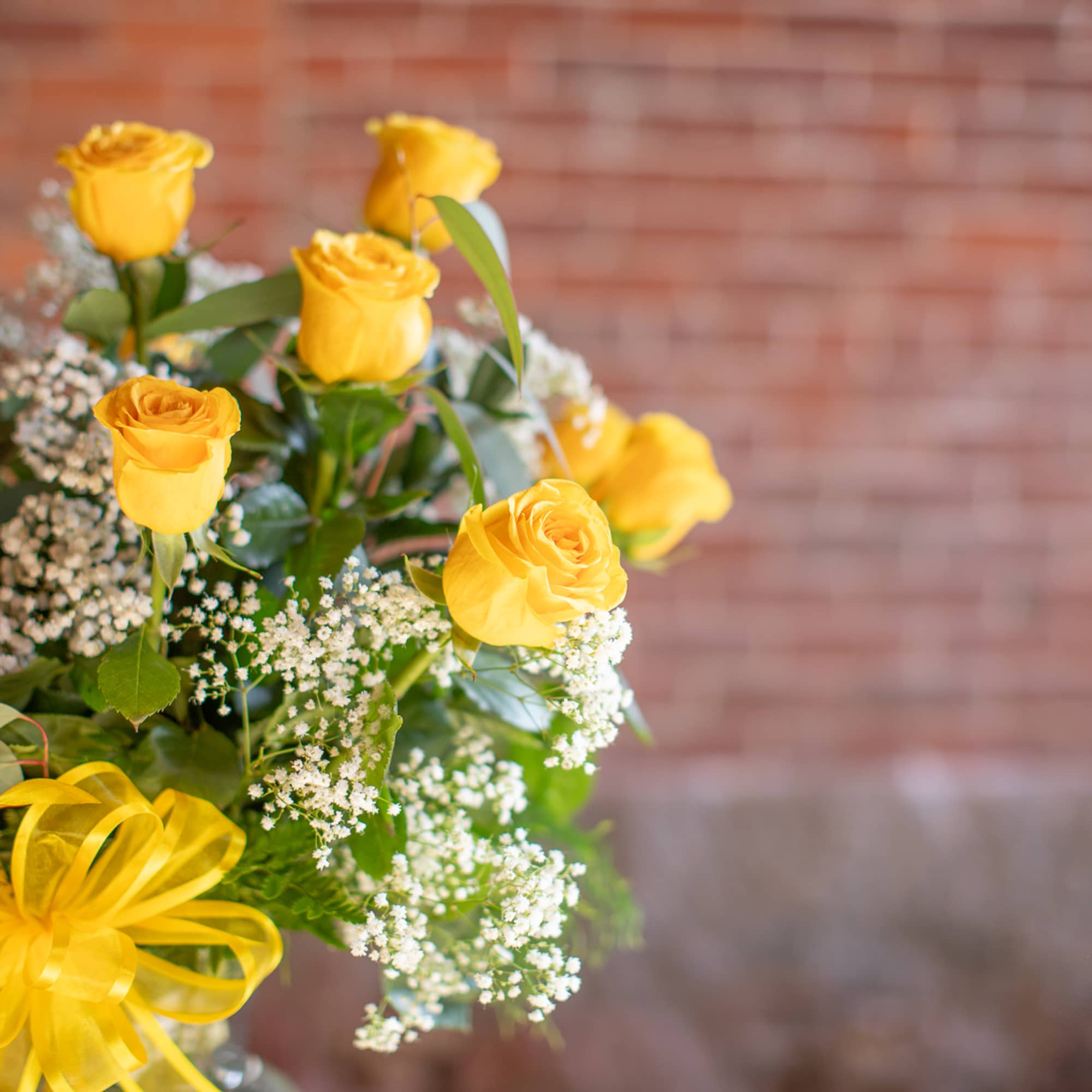 Yellow roses with white baby's breath and a yellow ribbon