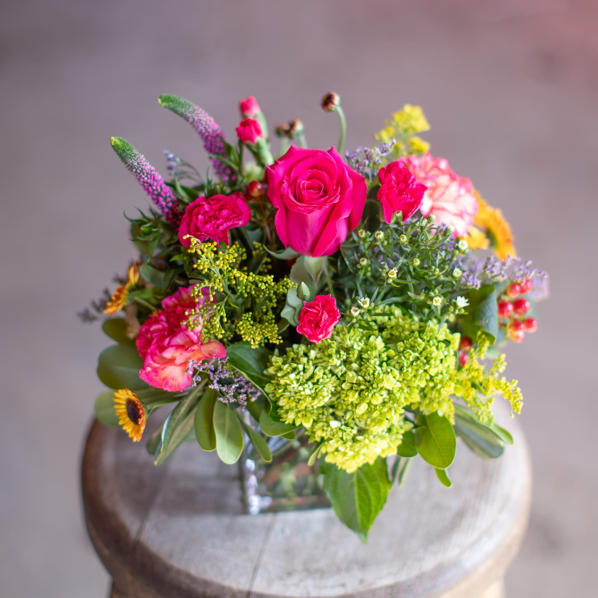 Bright mixed bouquet with pink roses and colorful blooms in a glass vase