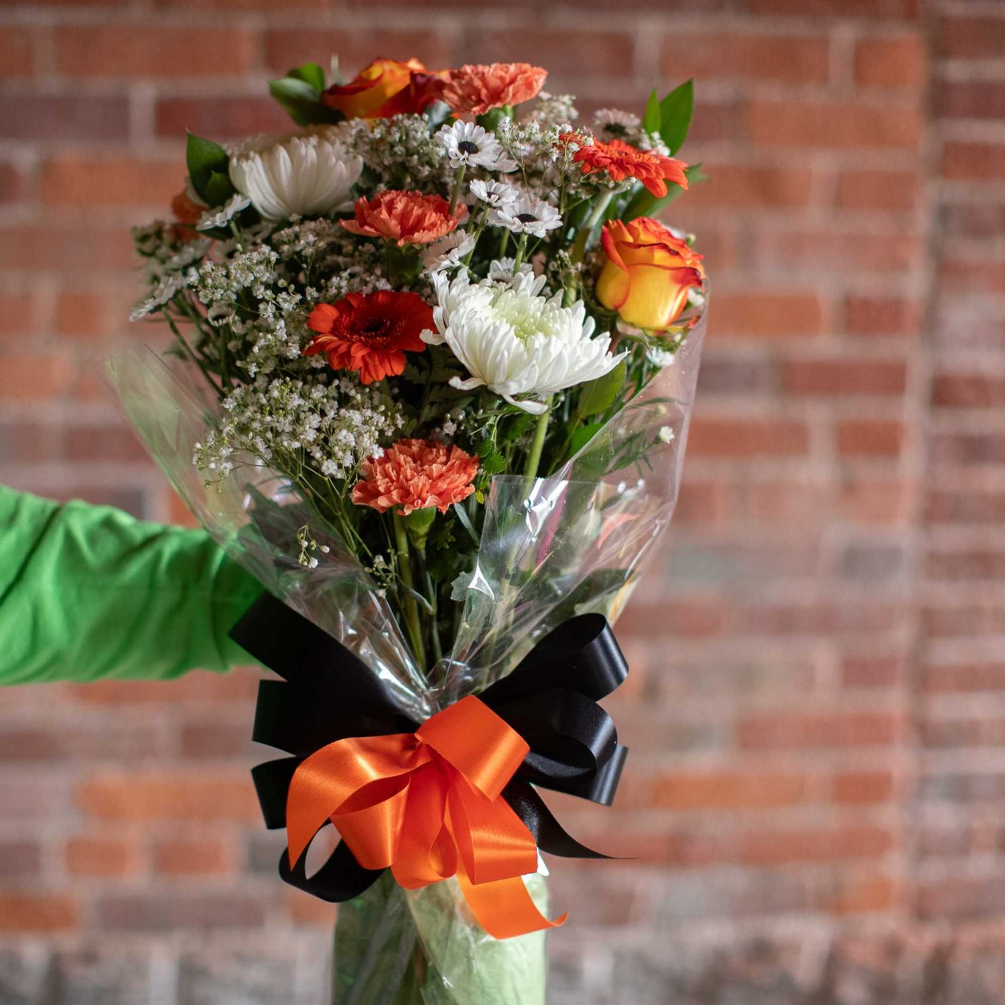 Mixed bouquet of orange, white, and red flowers wrapped in clear plastic