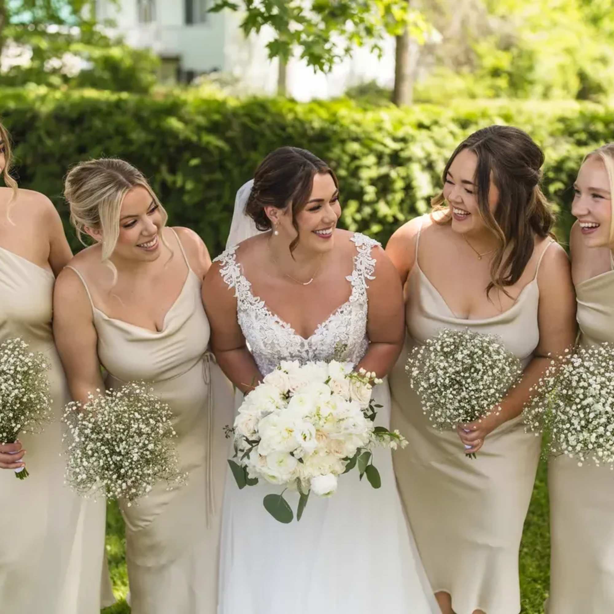 Bride with bridesmaids holding white bouquets outdoors