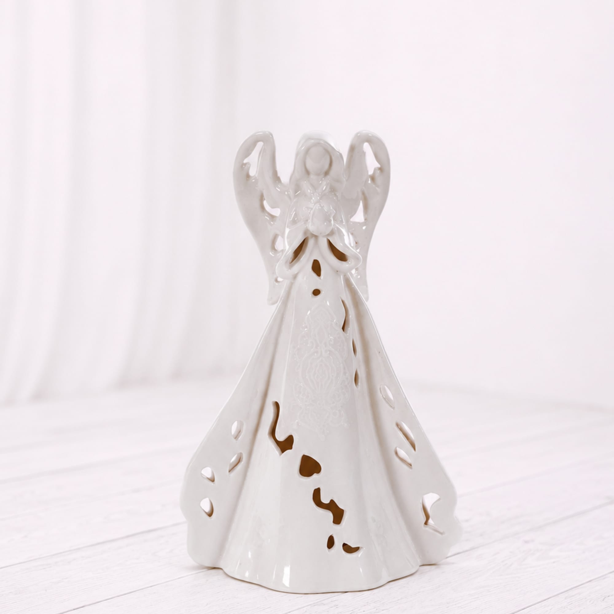 A peaceful white ceramic angel luminary with delicate cutout details and a