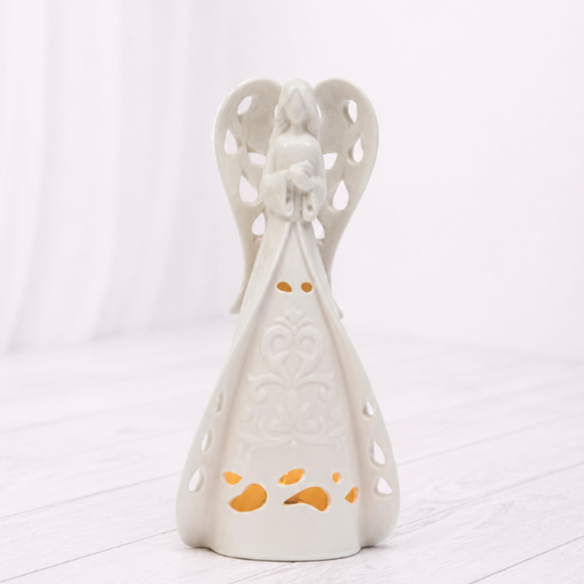 A peaceful white ceramic angel luminary with delicate cutout details and a