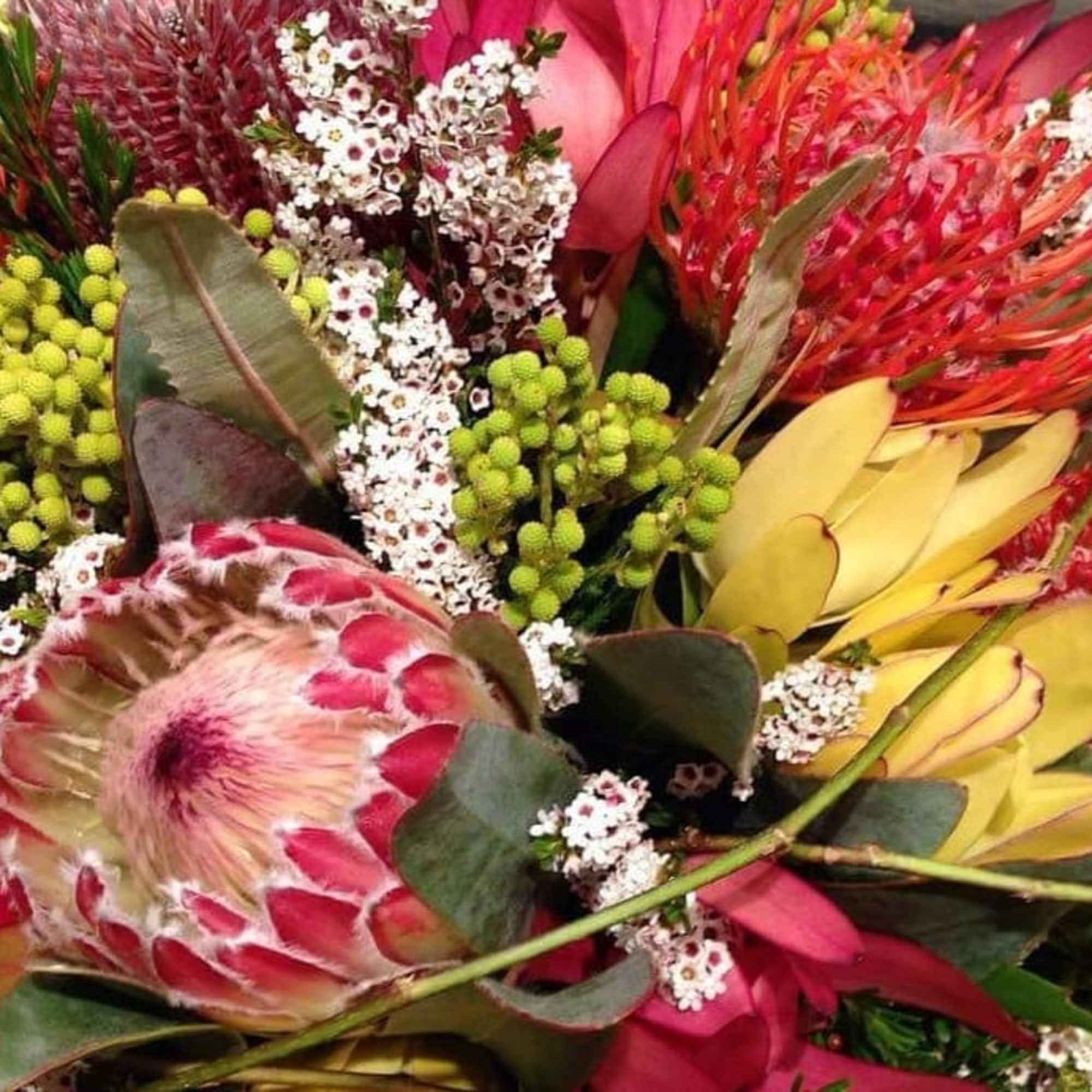 Tropical bouquet with protea, yellow blooms, and pink flowers