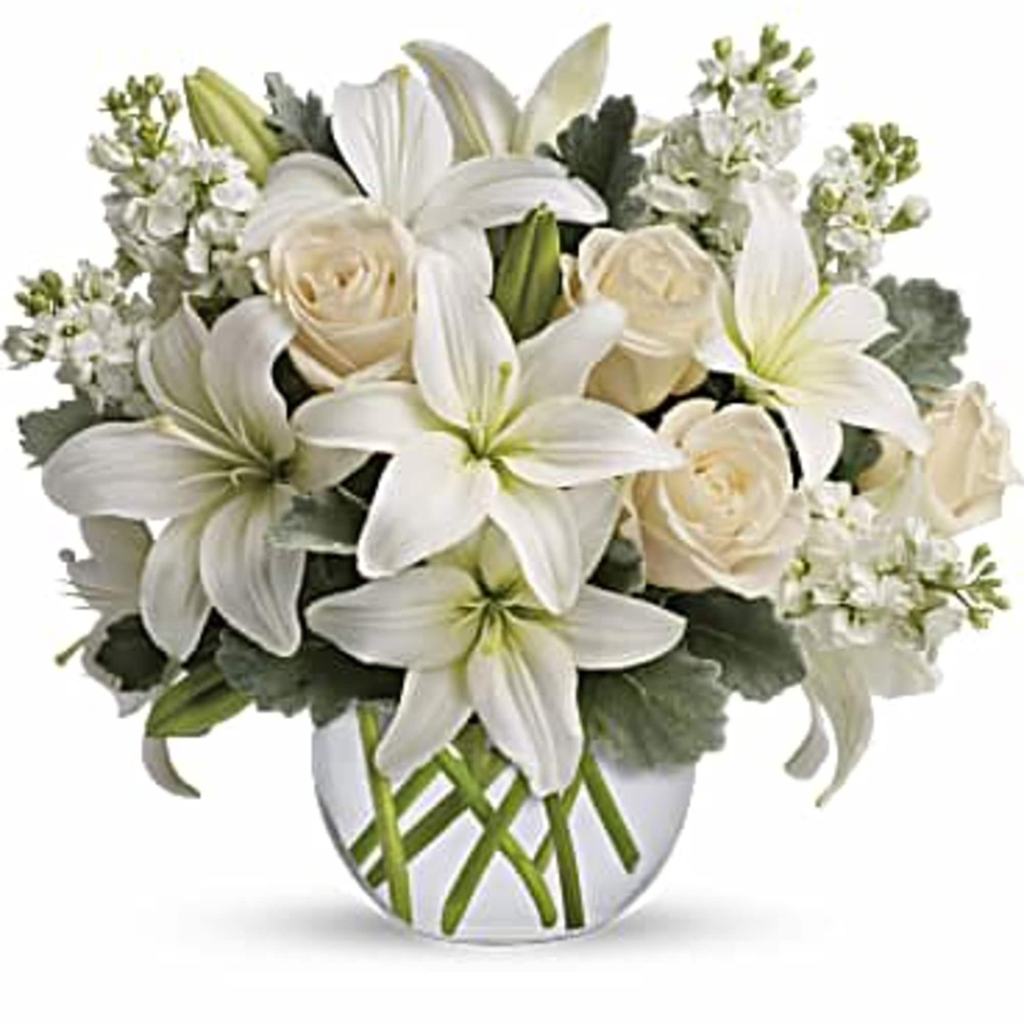White lilies and cream roses arranged in a clear glass vase