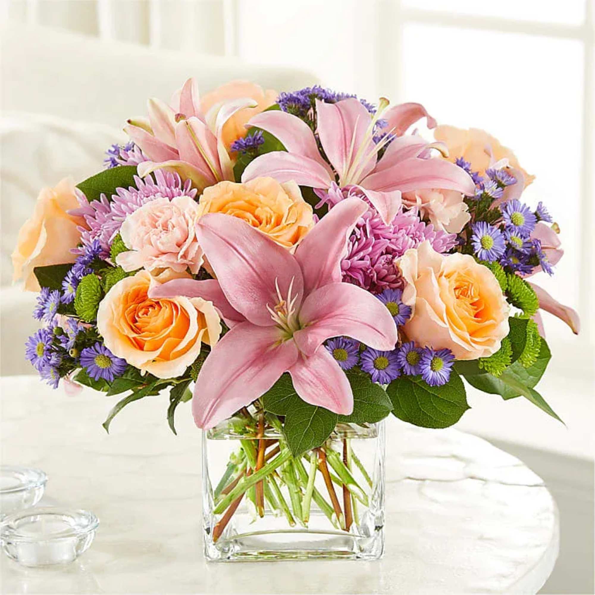 Pink lilies and peach roses in a clear glass vase