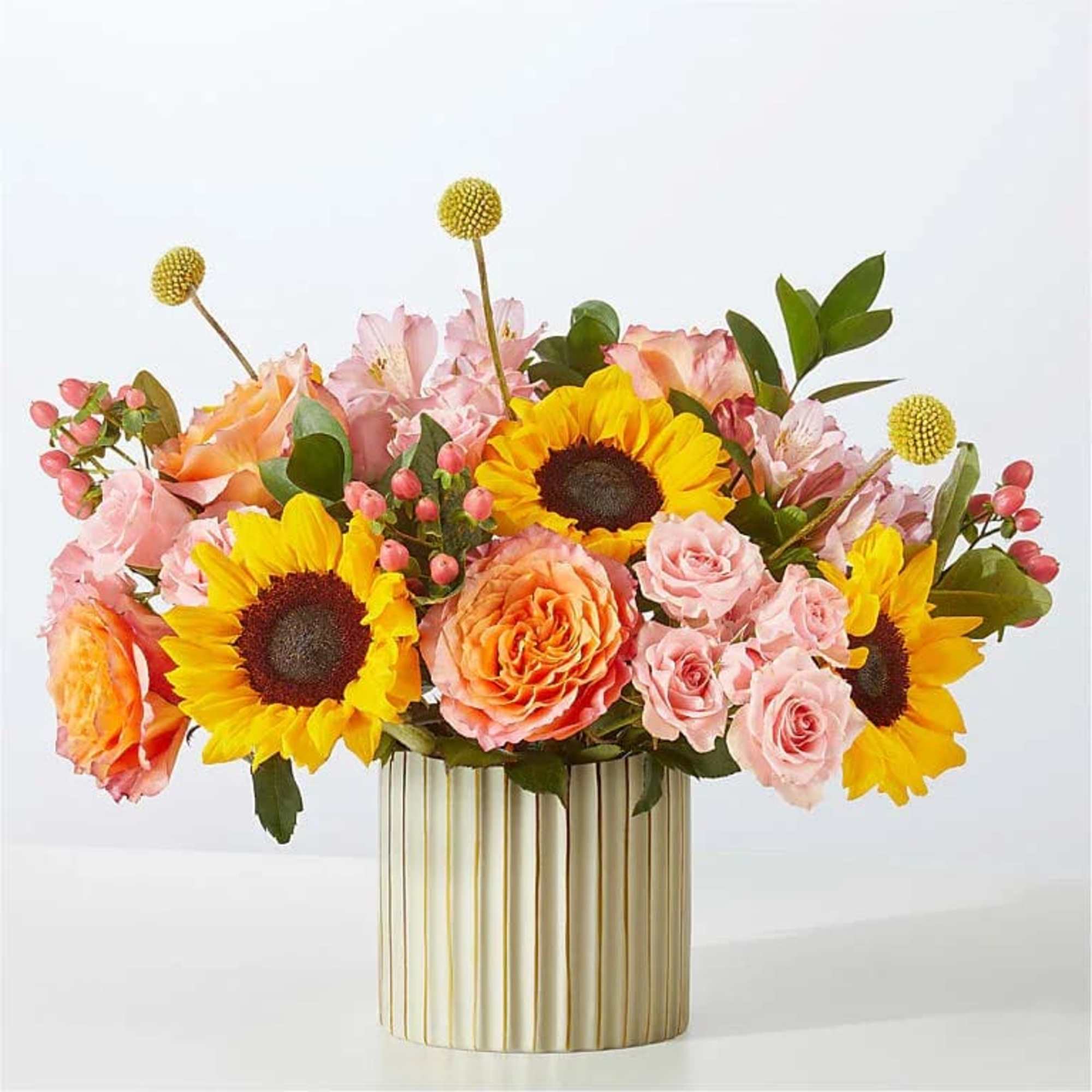 Mixed bouquet of sunflowers and pink roses in a striped gold vase