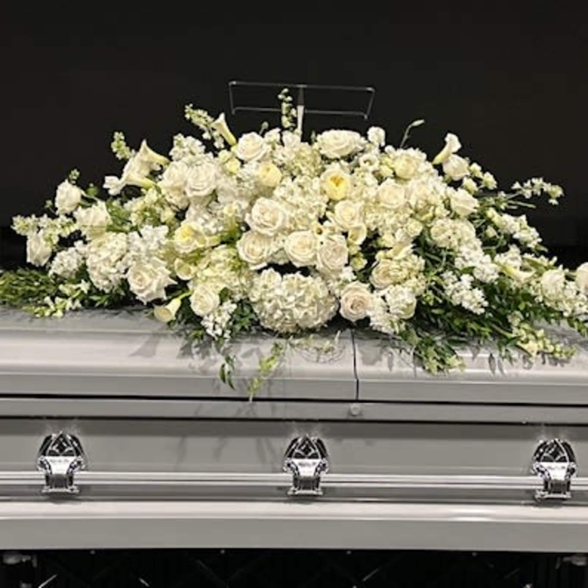 White floral casket spray on a silver casket
