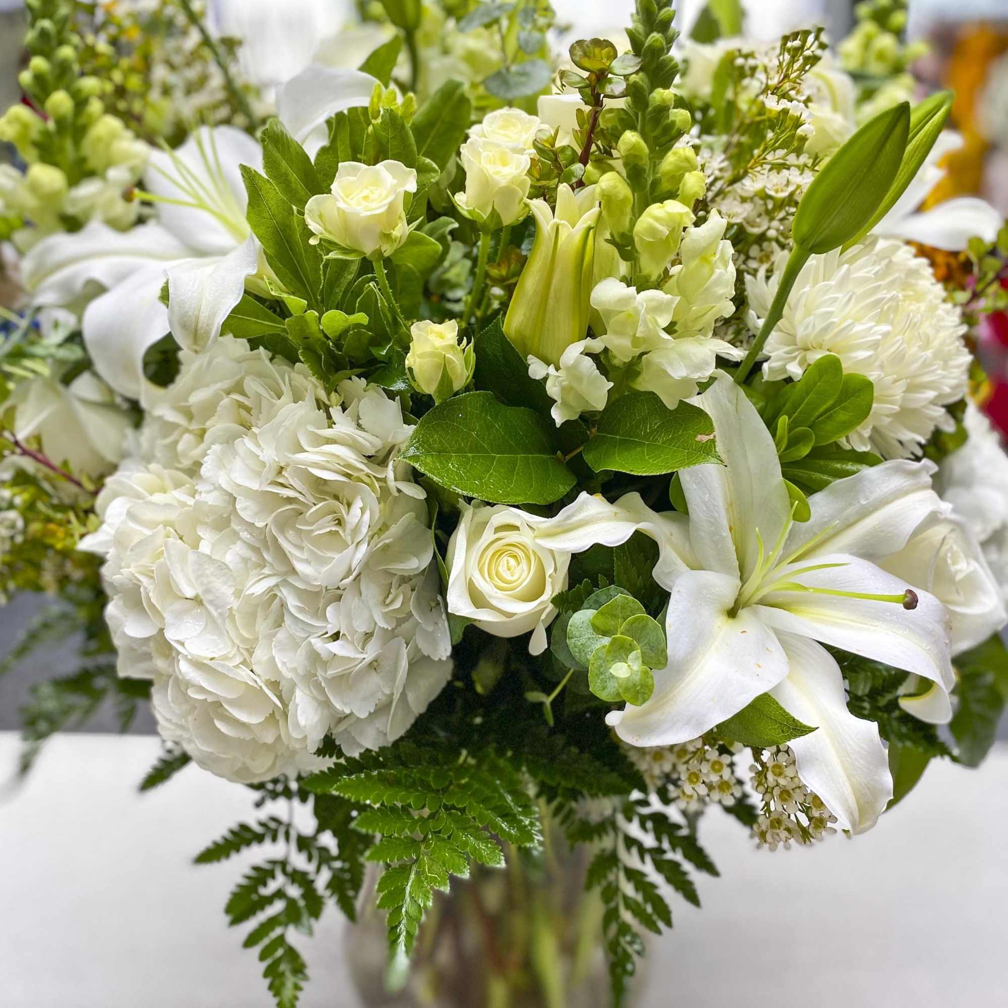 White floral bouquet with lilies, roses, and hydrangeas in a vase
