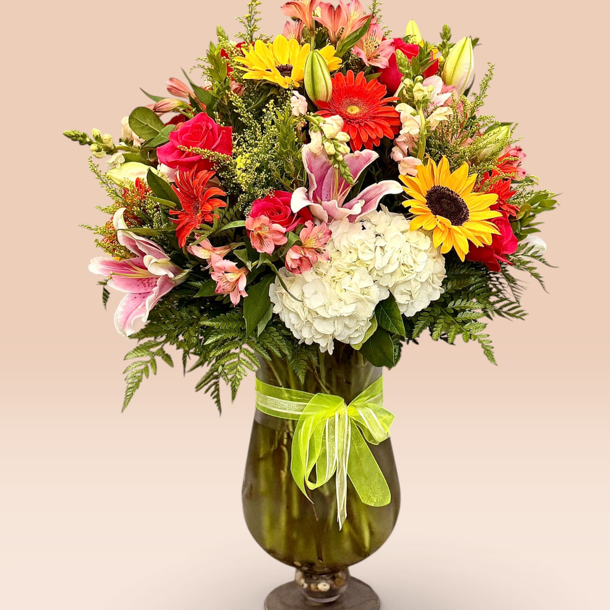 Mixed bouquet in a tall glass vase with a green ribbon