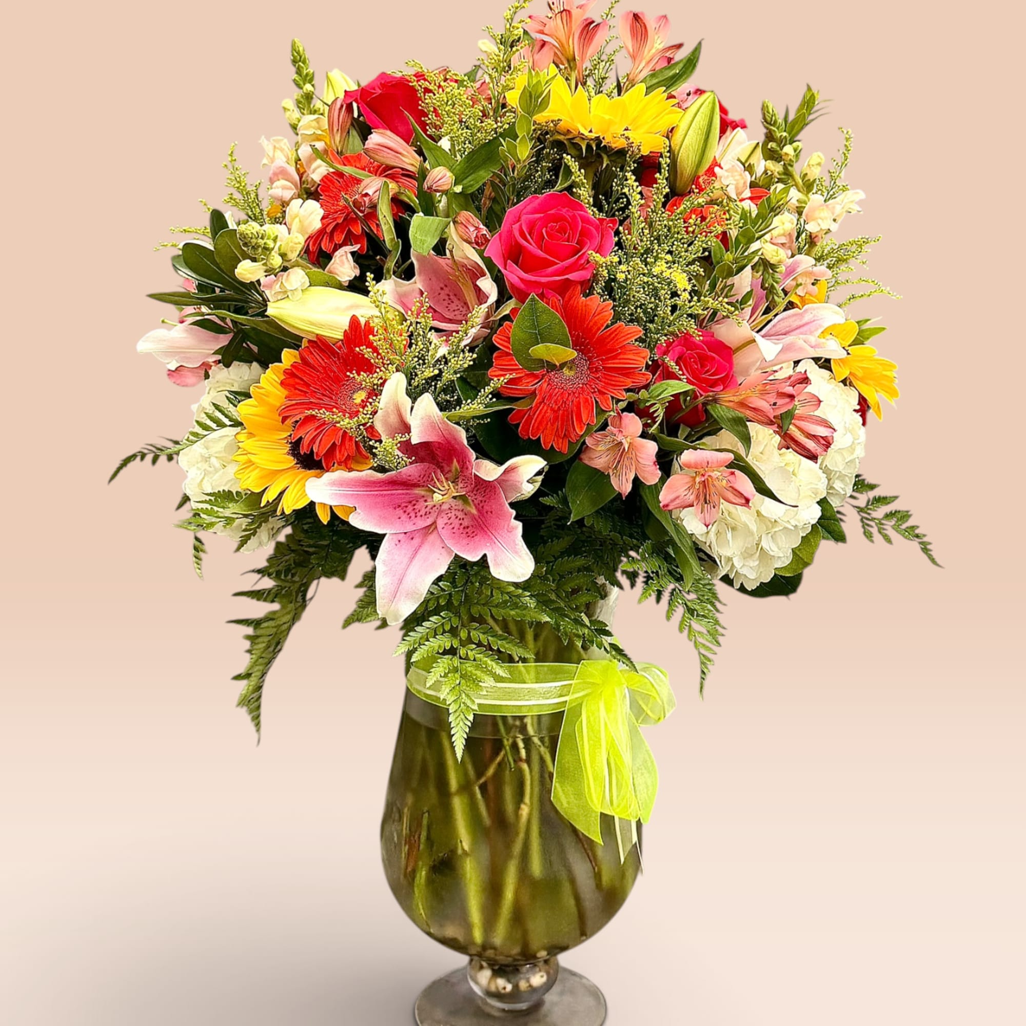 Mixed bouquet of roses, lilies, gerbera daisies, and hydrangeas in a glass vase