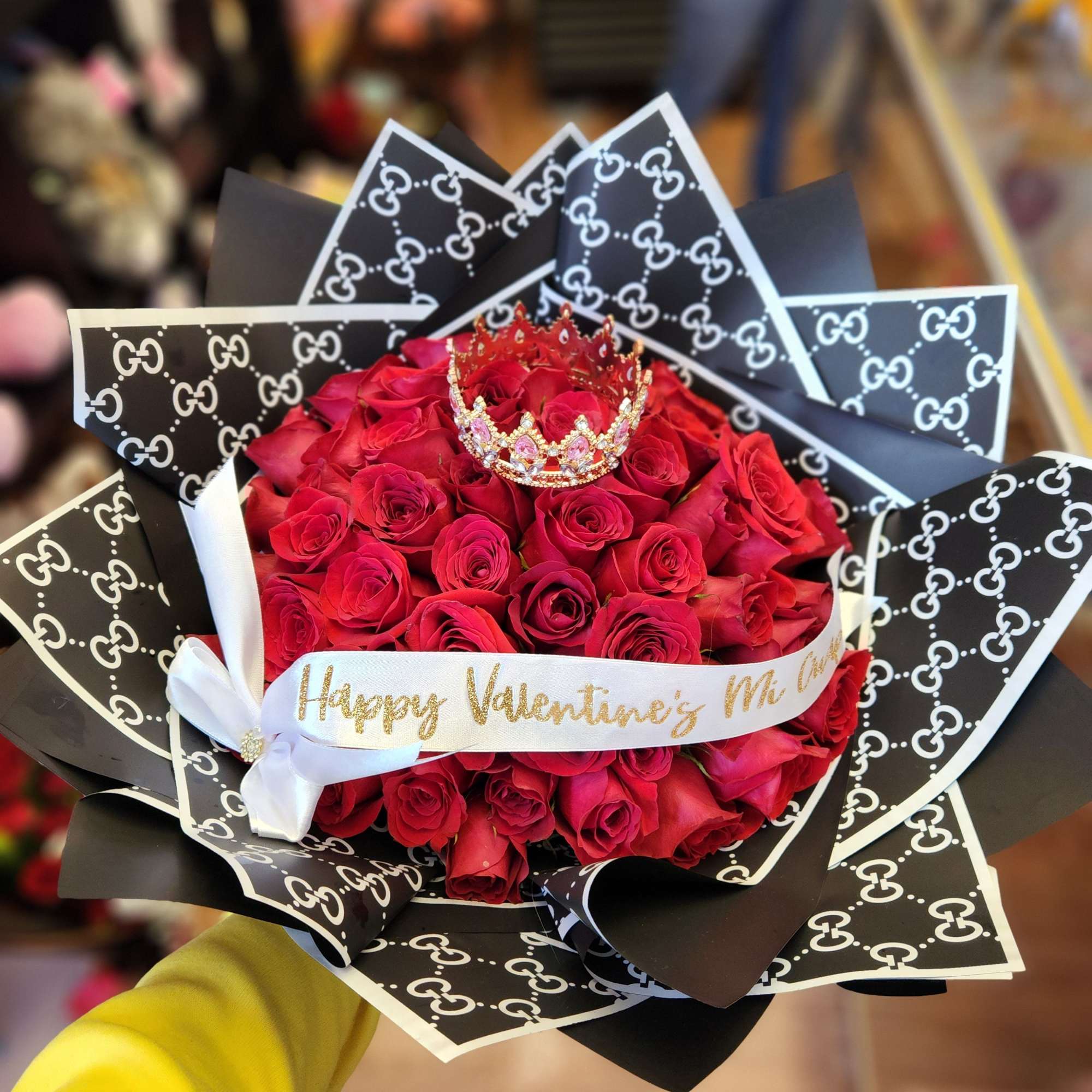 Bouquet of red roses with a small crown and patterned black wrapping