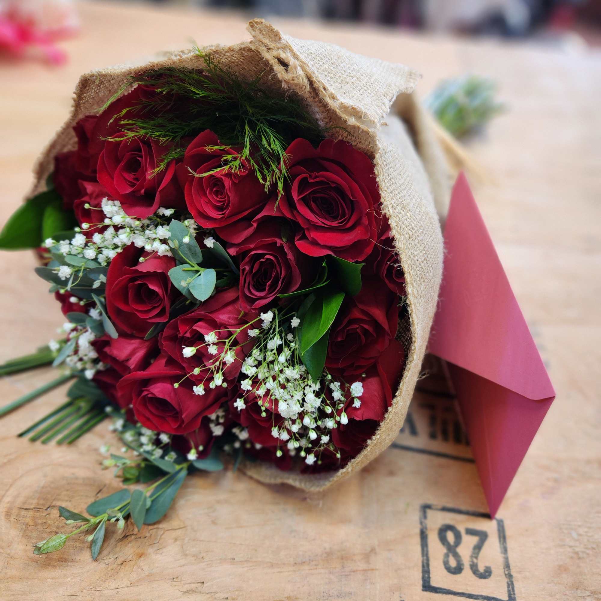 Bouquet of red roses wrapped in burlap with pink paper