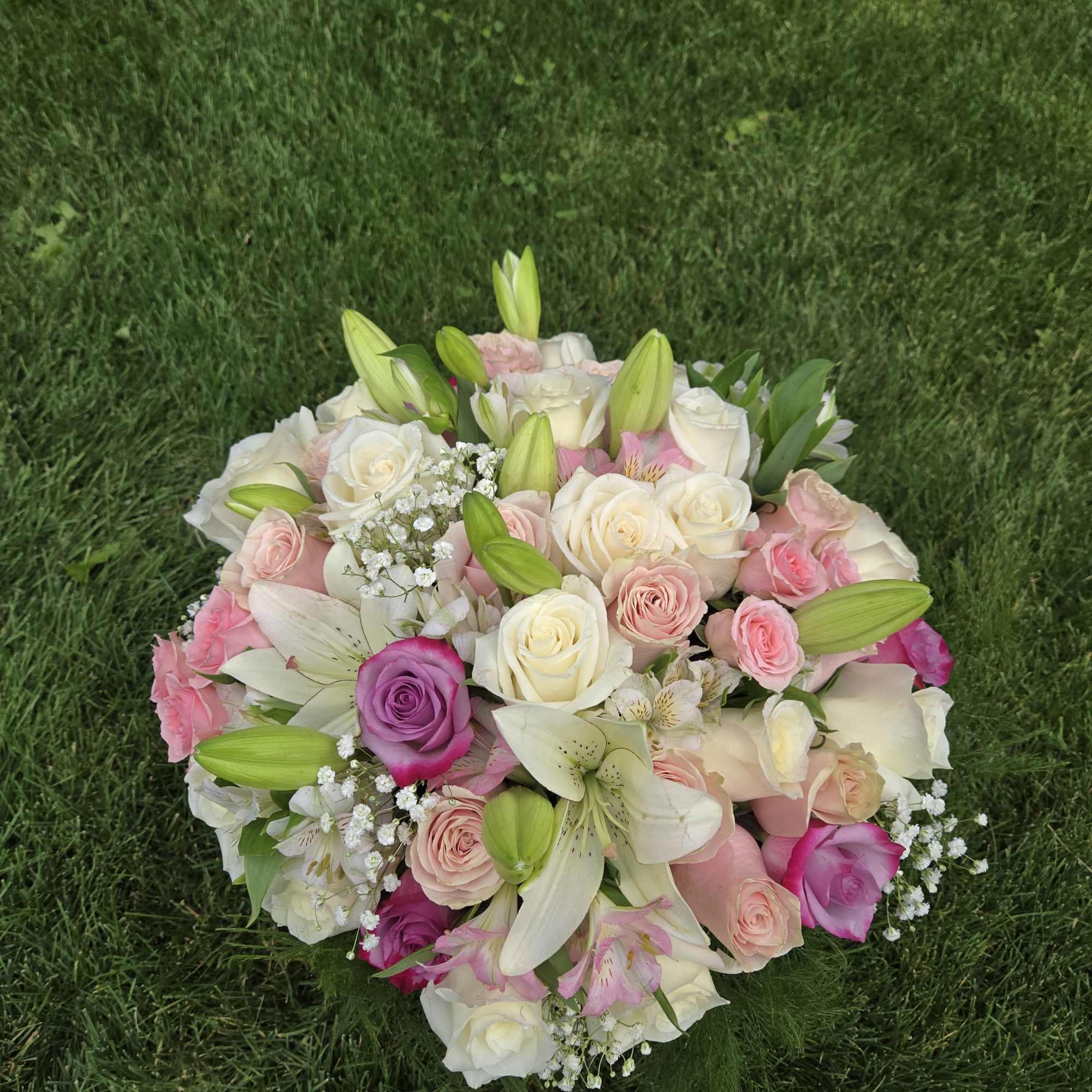 Round bouquet of pink and white roses with lilies on grass