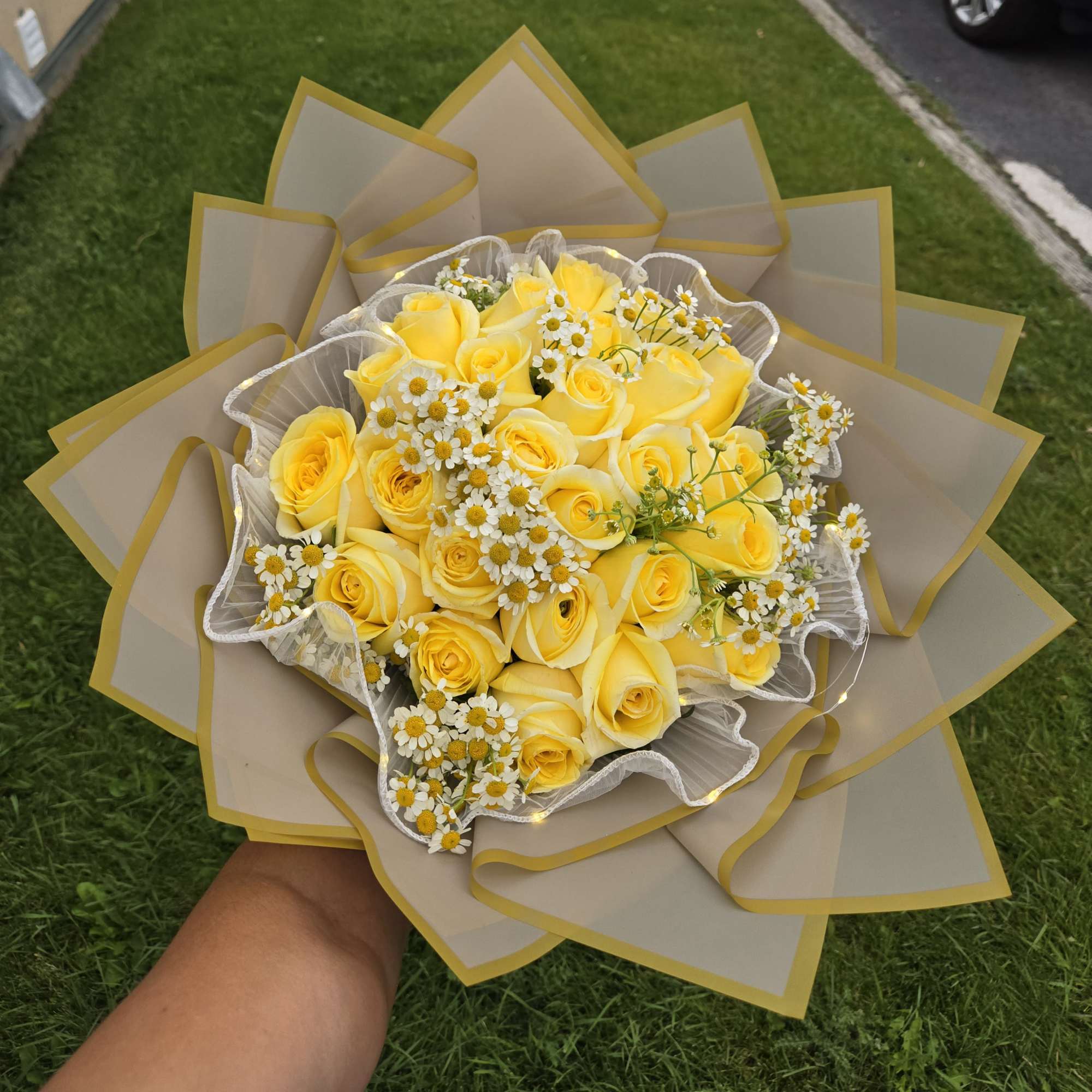 Yellow rose bouquet with small white daisies wrapped in beige paper