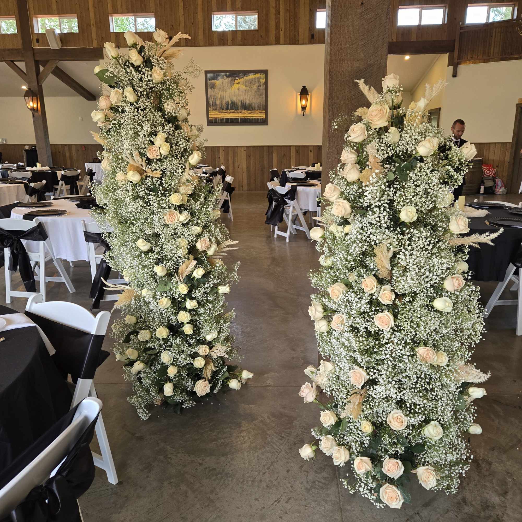 Tall floral columns of white and blush roses with baby's breath in a reception hall