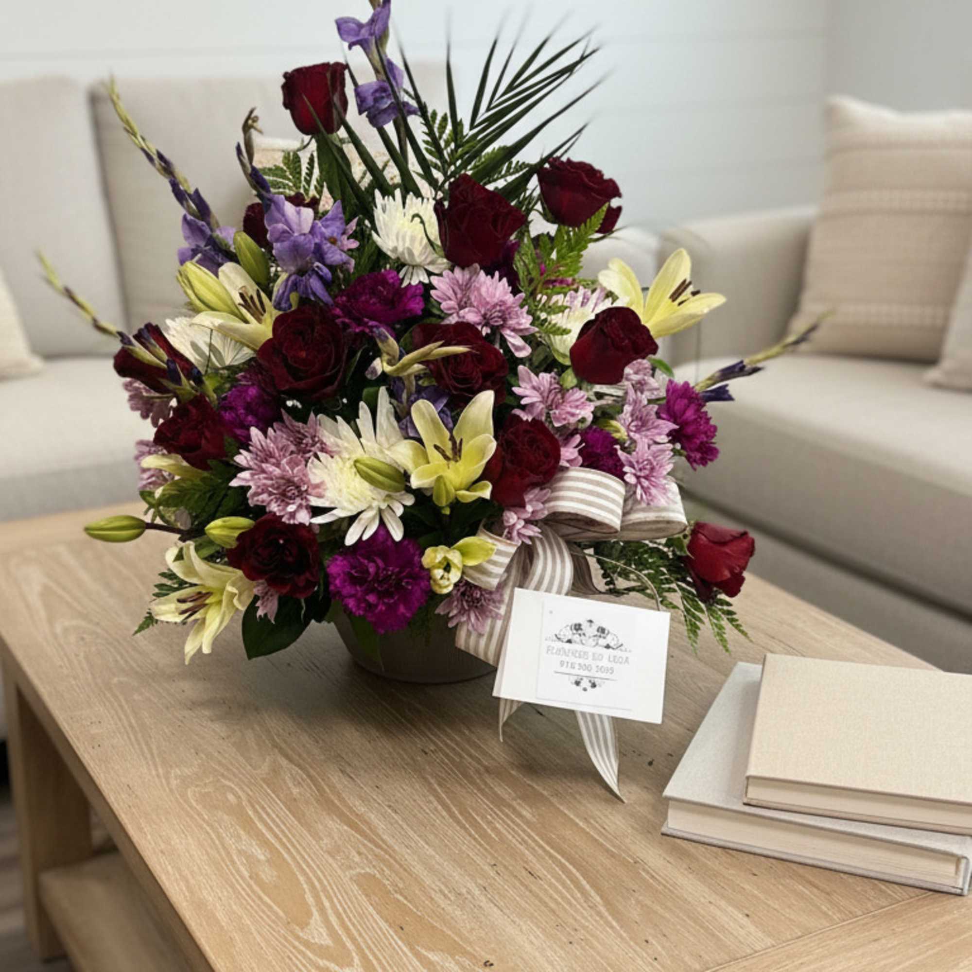 Mixed bouquet in a low vase with roses, lilies, and purple flowers