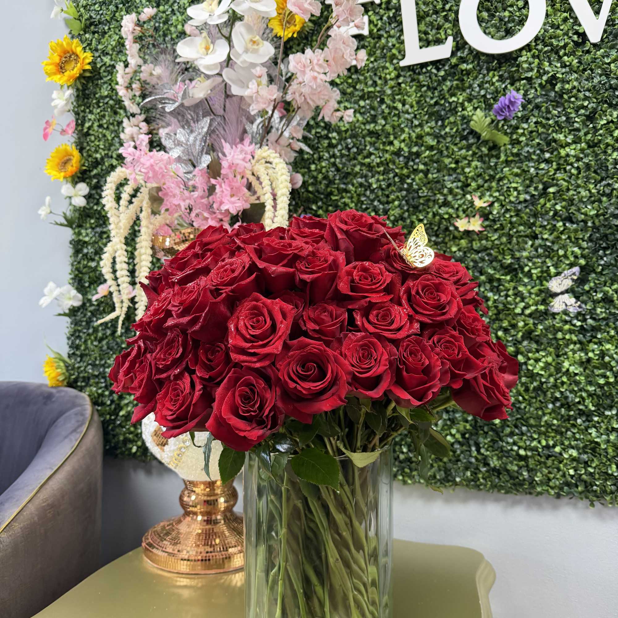 100 BEAUTIFULL RED ROSES ARRANGED NICELY IN A LARGE CLEAR VASE WITH