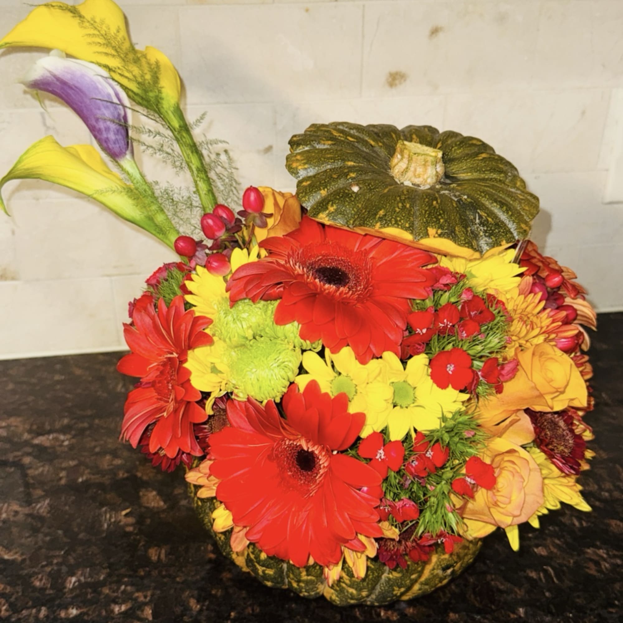 This festive holiday arrangement is designed inside a natural pumpkin vessel, creating