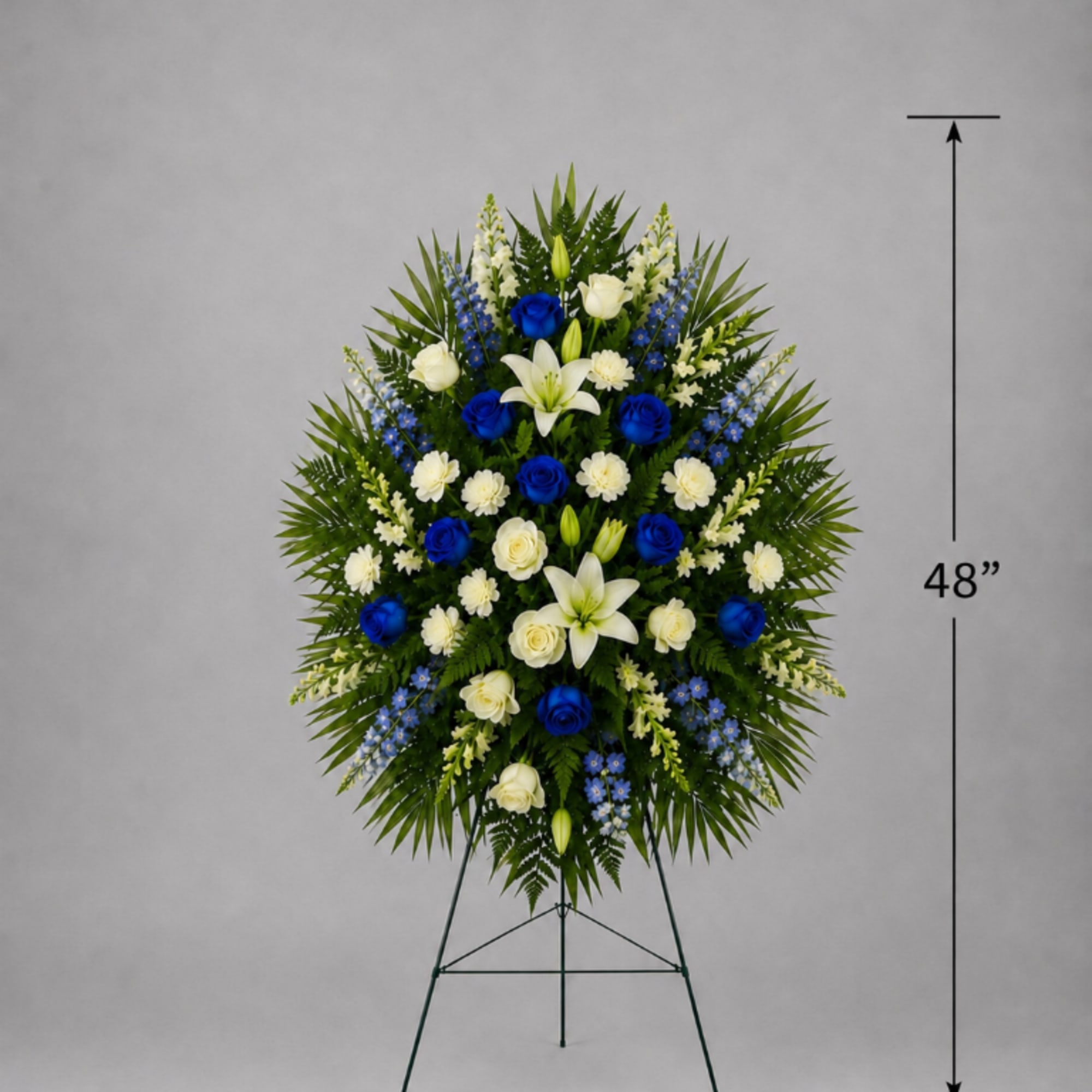 Large standing floral spray with white lilies, blue roses, and white roses on a metal easel
