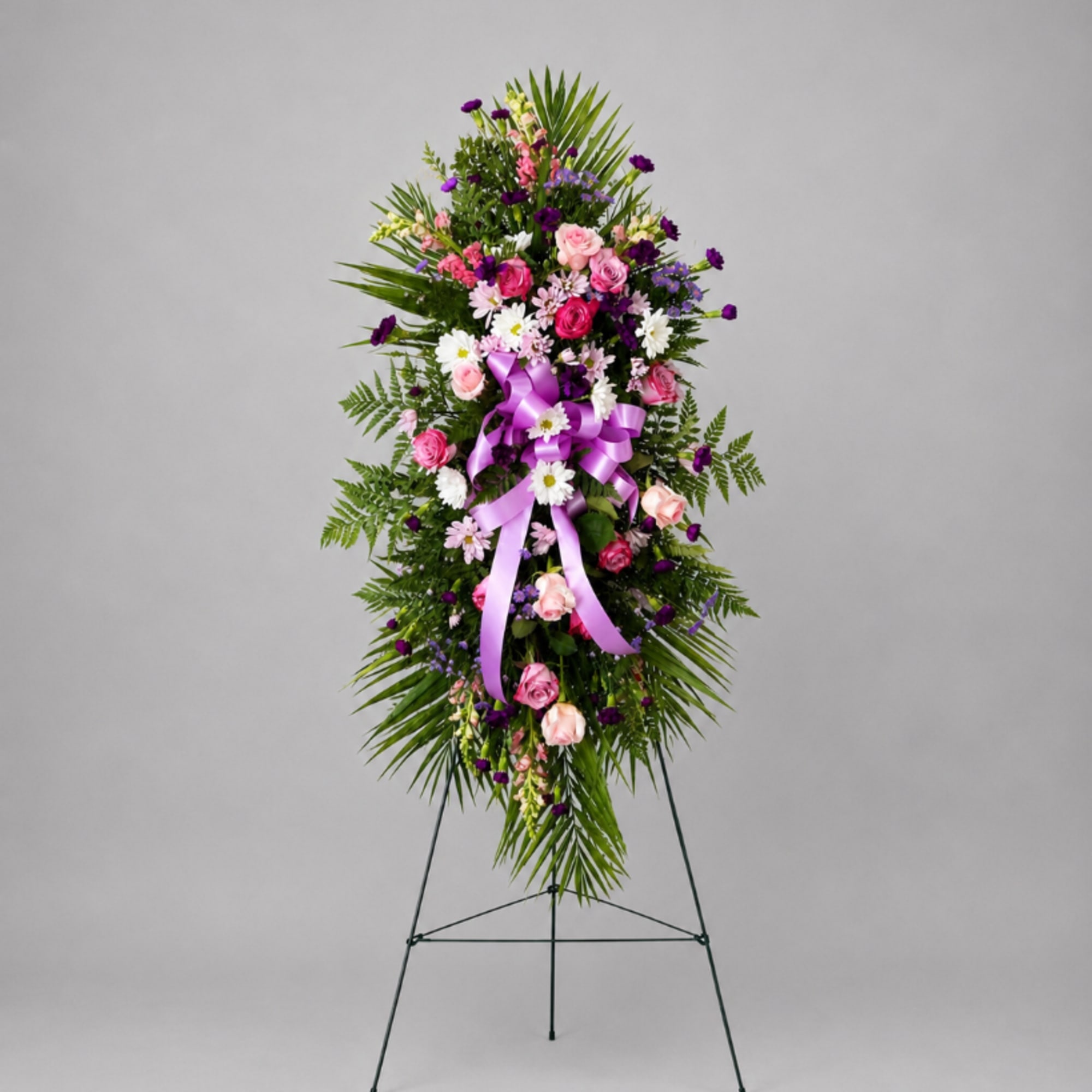 Standing floral spray with pink and purple flowers on a metal easel