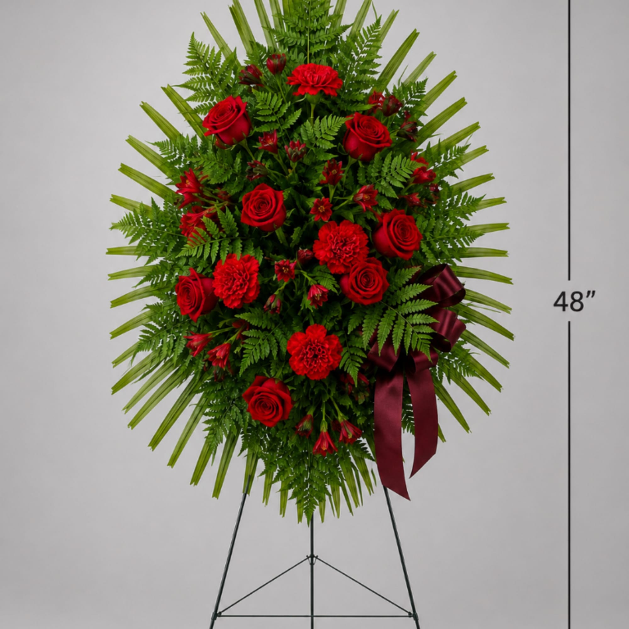 Red rose and carnation standing spray on an easel with a burgundy ribbon