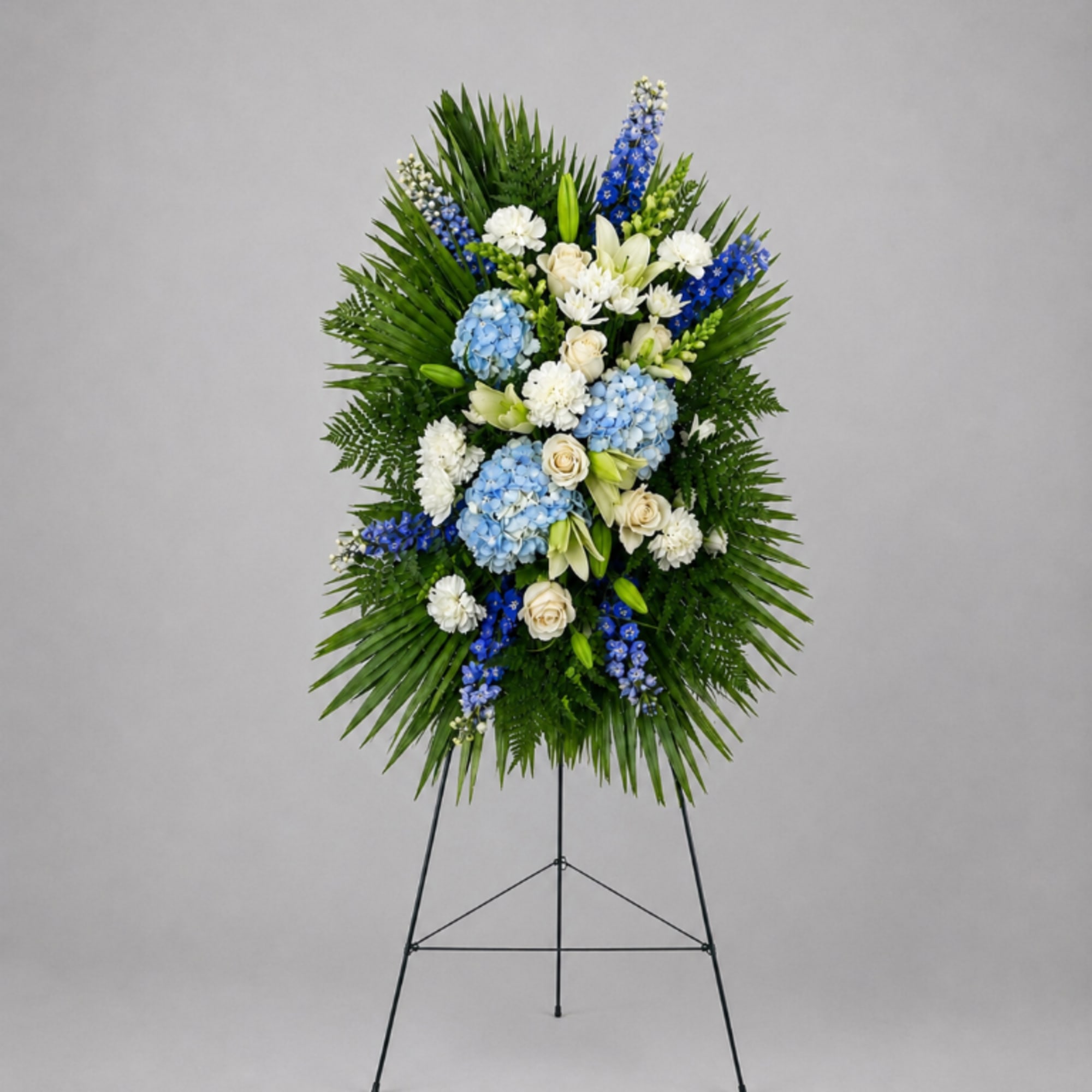 Standing floral wreath with blue and white flowers on an easel
