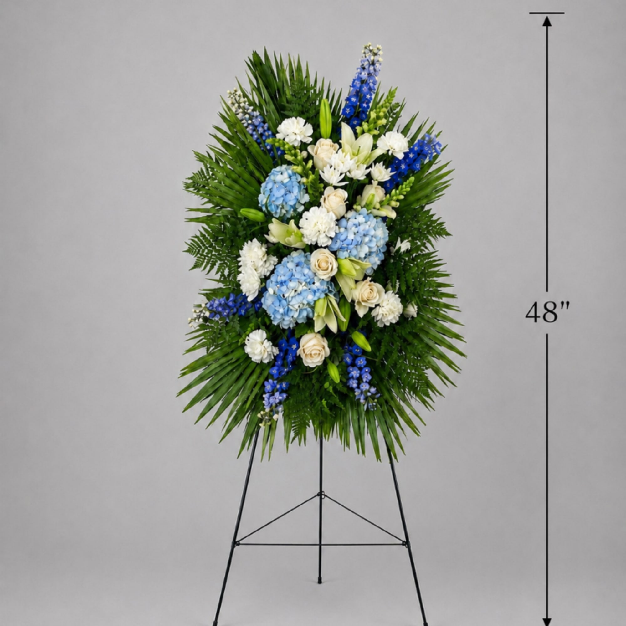 Tall blue, white, and cream funeral spray on a stand