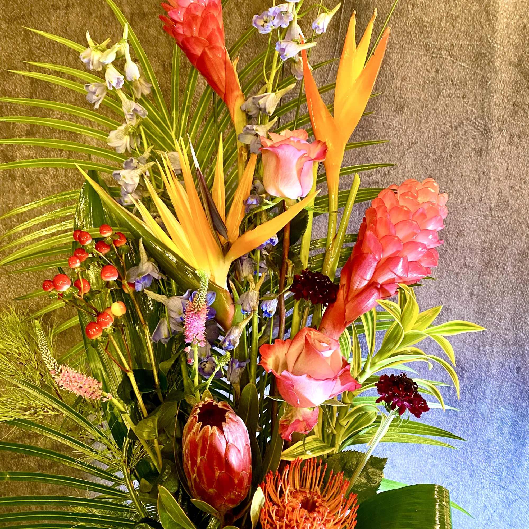Tropical arrangement with pink ginger, orange bird-of-paradise, and protea