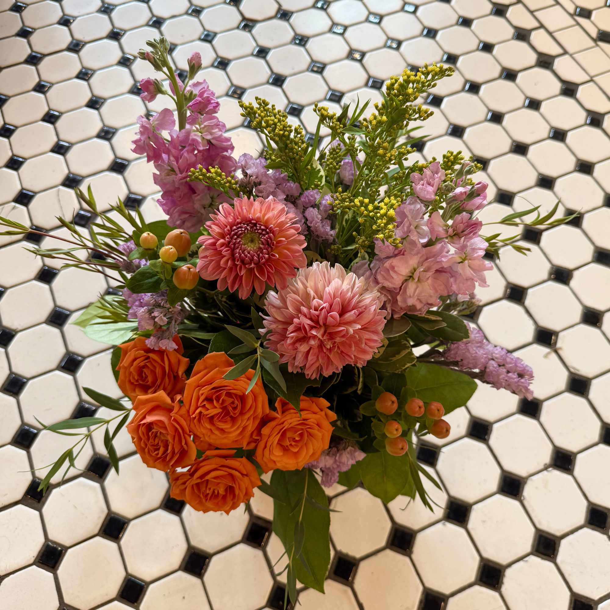 Bouquet of orange roses, pink blooms, and yellow filler flowers