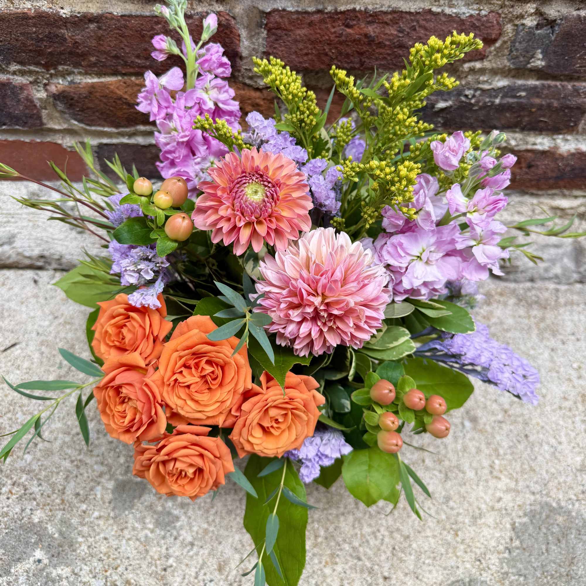 Bouquet of orange roses, pink dahlias, and lavender flowers