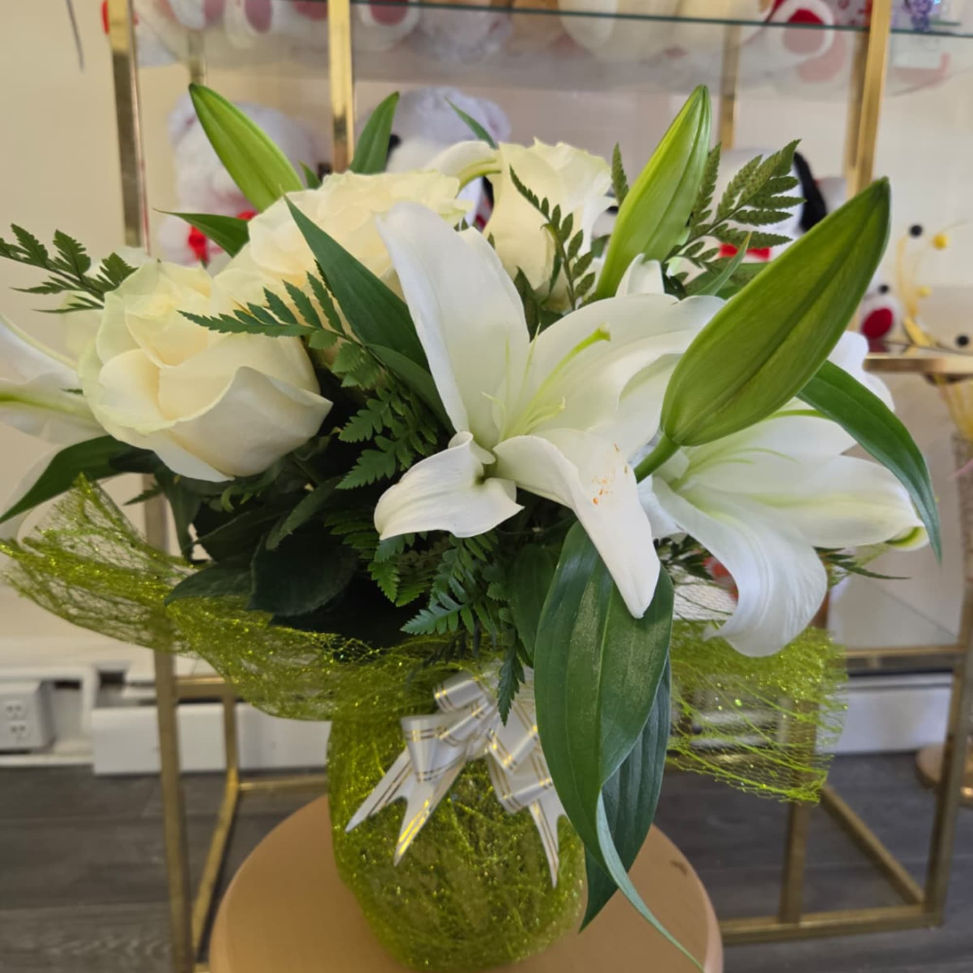 White lilies and cream roses in a green wrapped vase arrangement