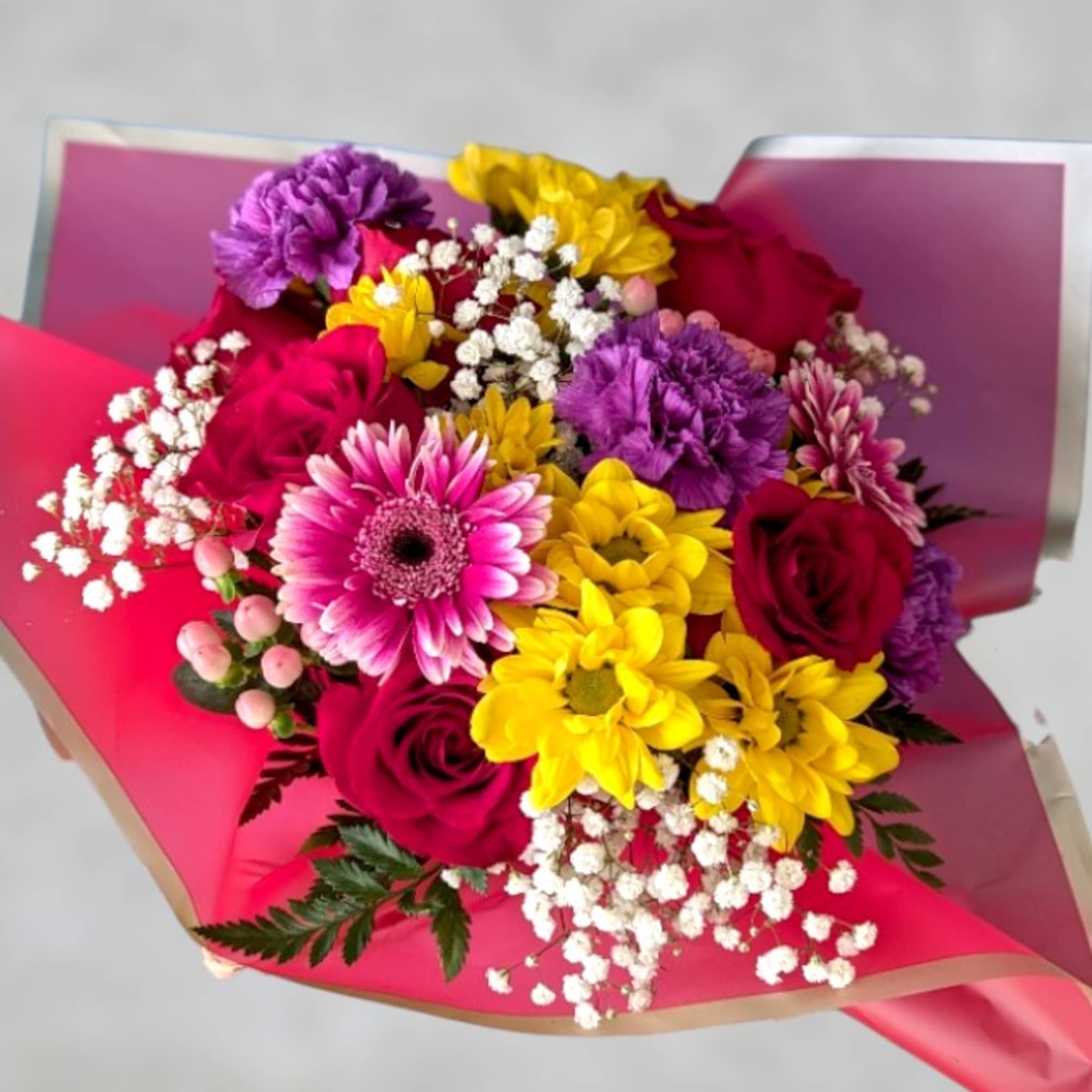 Bouquet of pink, yellow, and purple flowers wrapped in bright paper