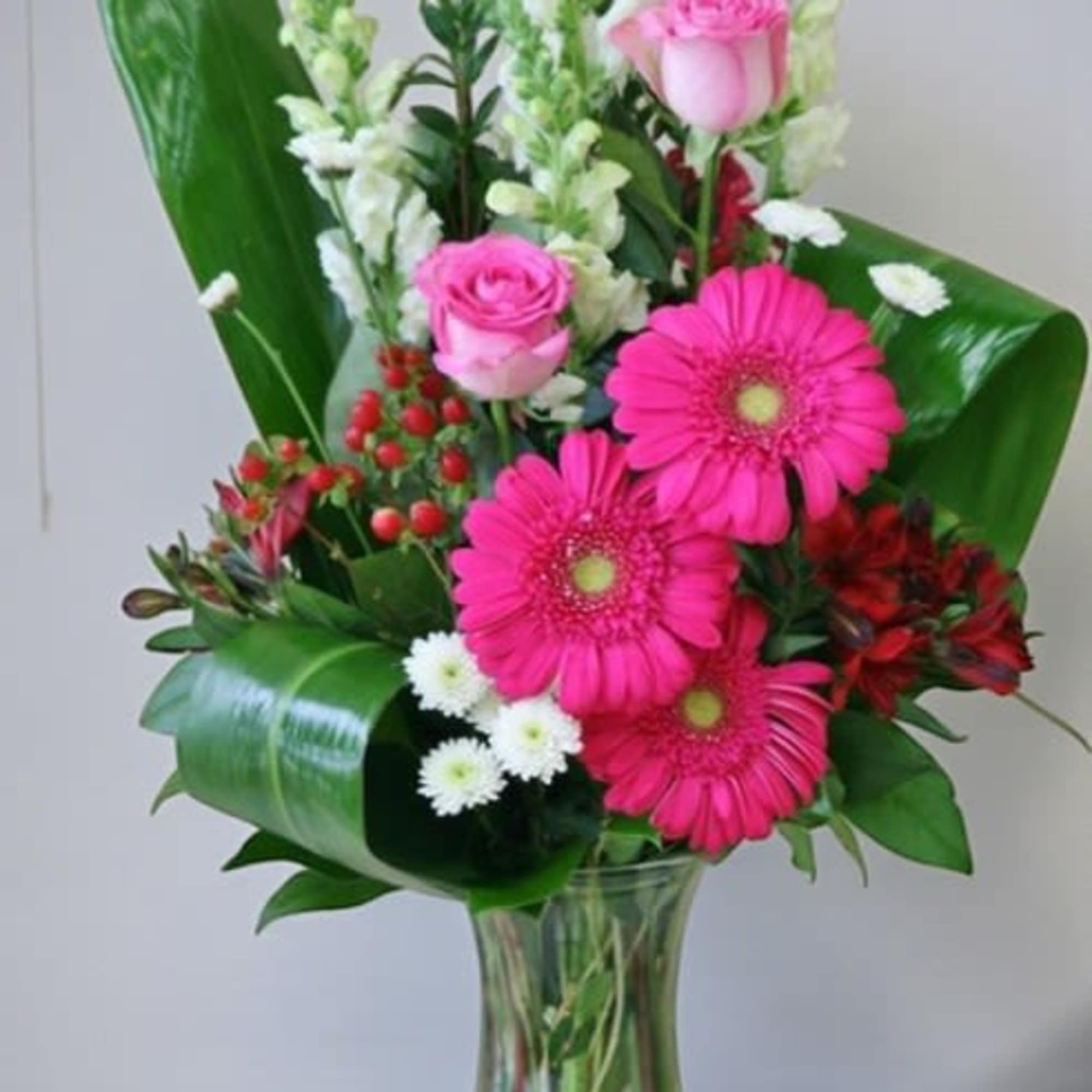 Pink roses and gerbera daisies in a clear glass vase