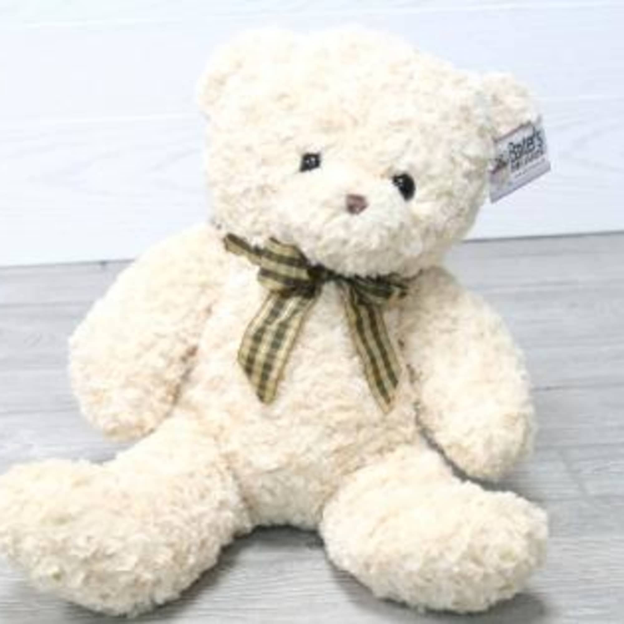 Cream teddy bear with a plaid ribbon around its neck