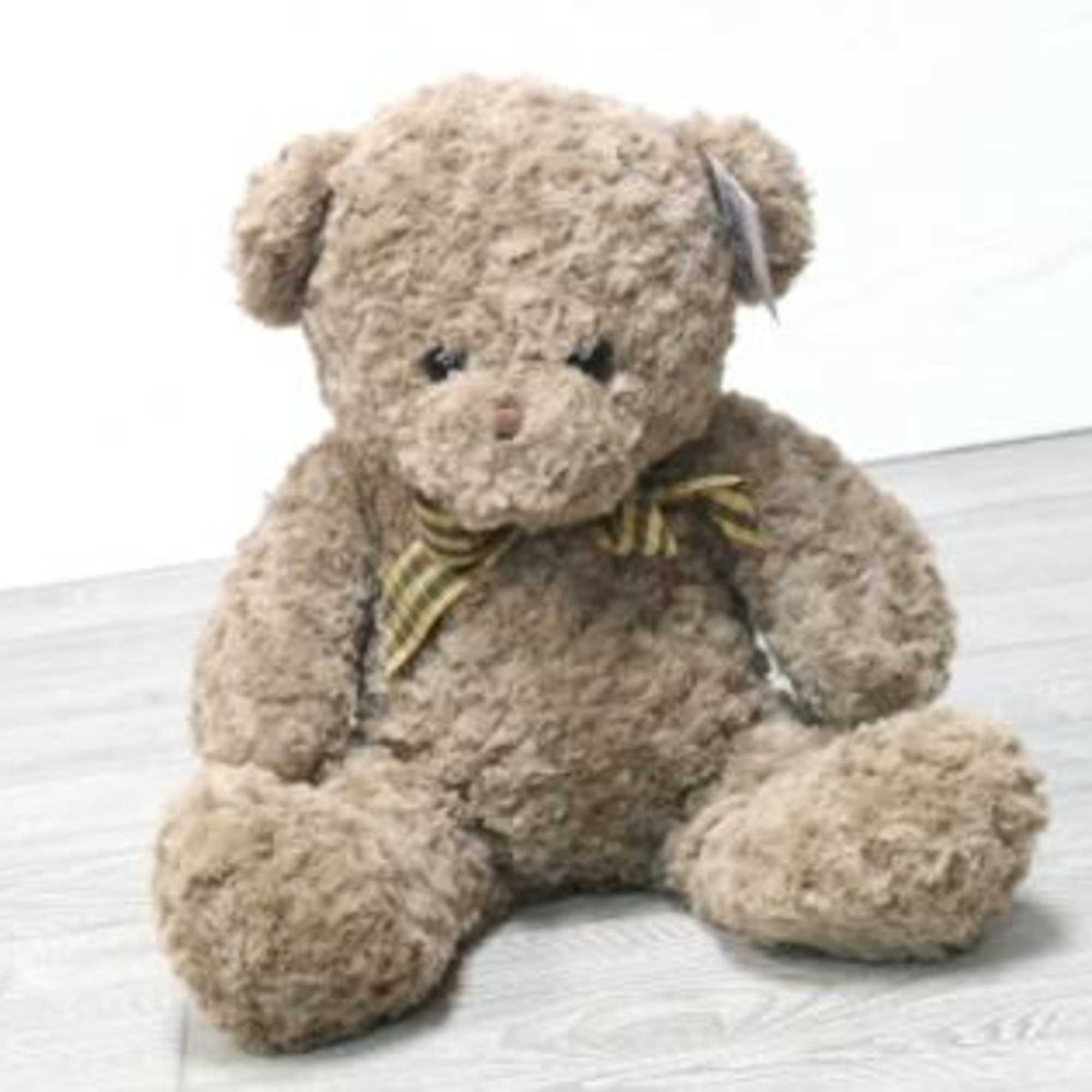 Plush teddy bear with a striped bow sitting on a light surface