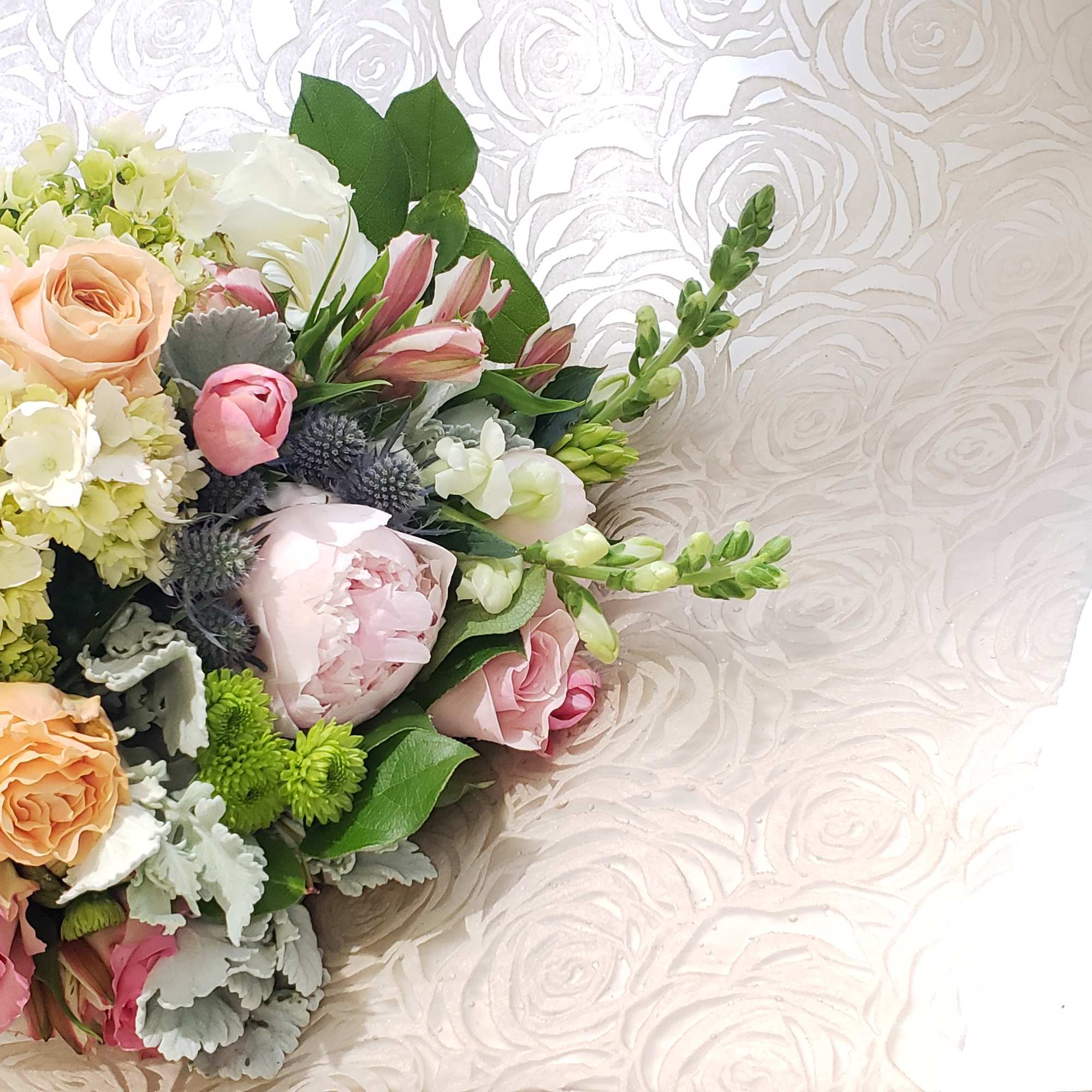Bouquet of pink and peach roses with pale hydrangeas and mixed greenery