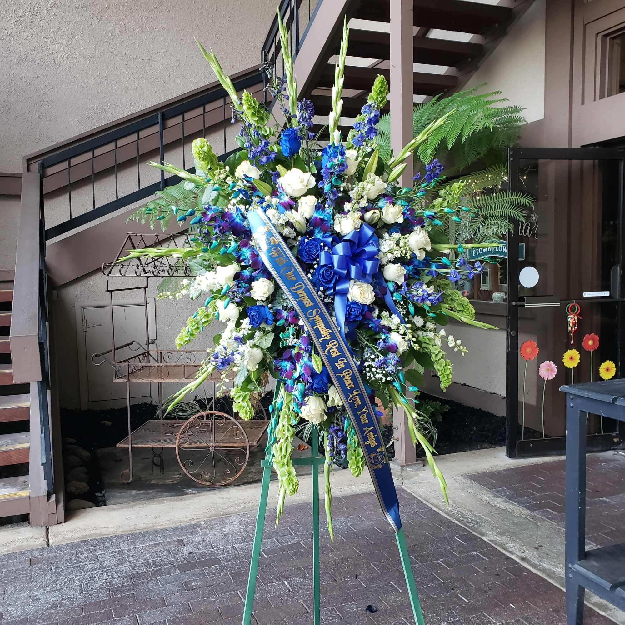 Large blue and white standing floral spray with a ribbon on an easel