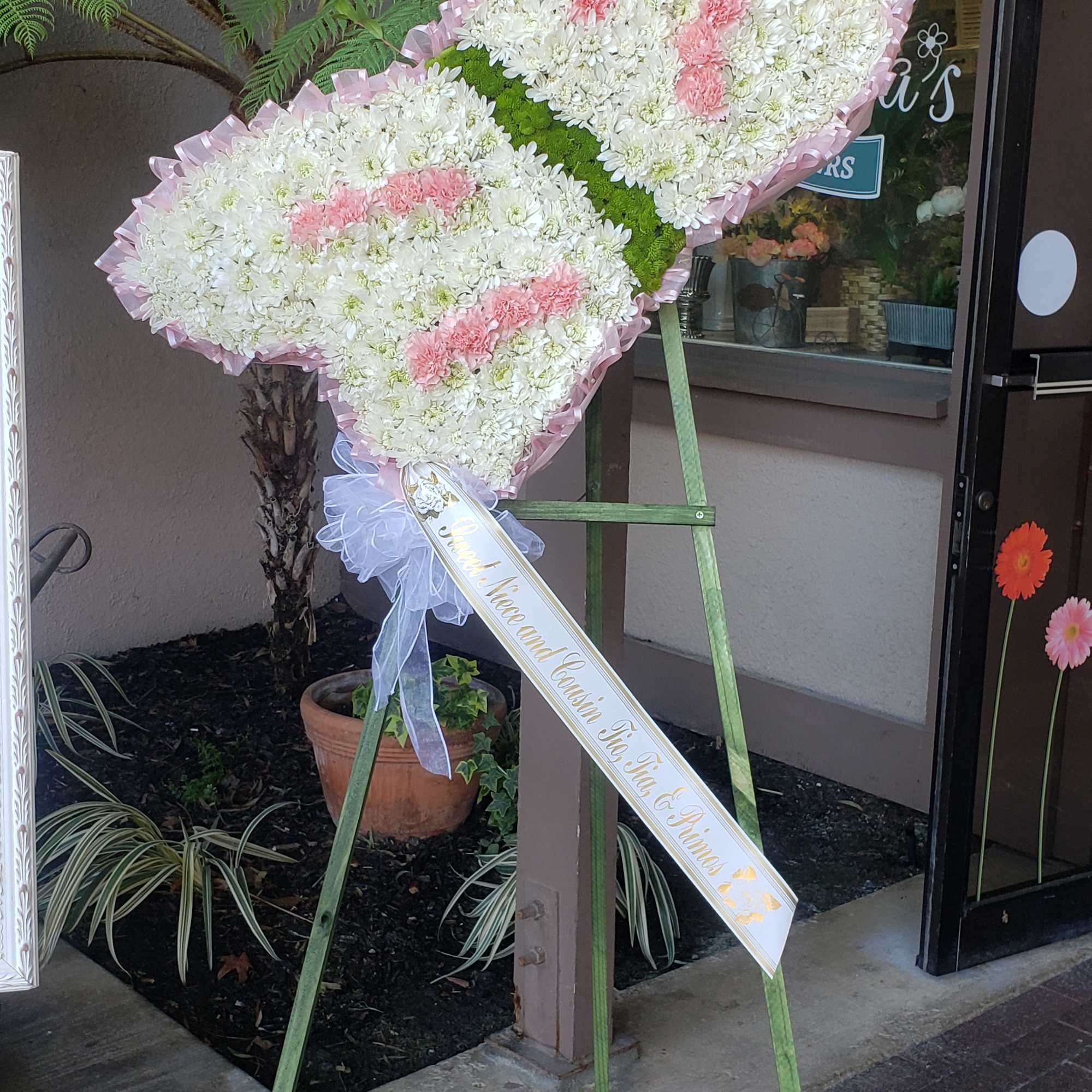 Heart-shaped standing floral tribute with white and pink flowers on an easel