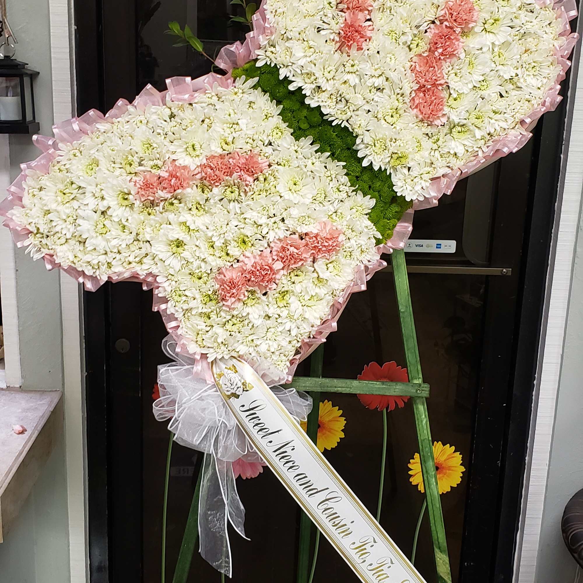 Butterfly-shaped floral standing spray with white and pink flowers on an easel
