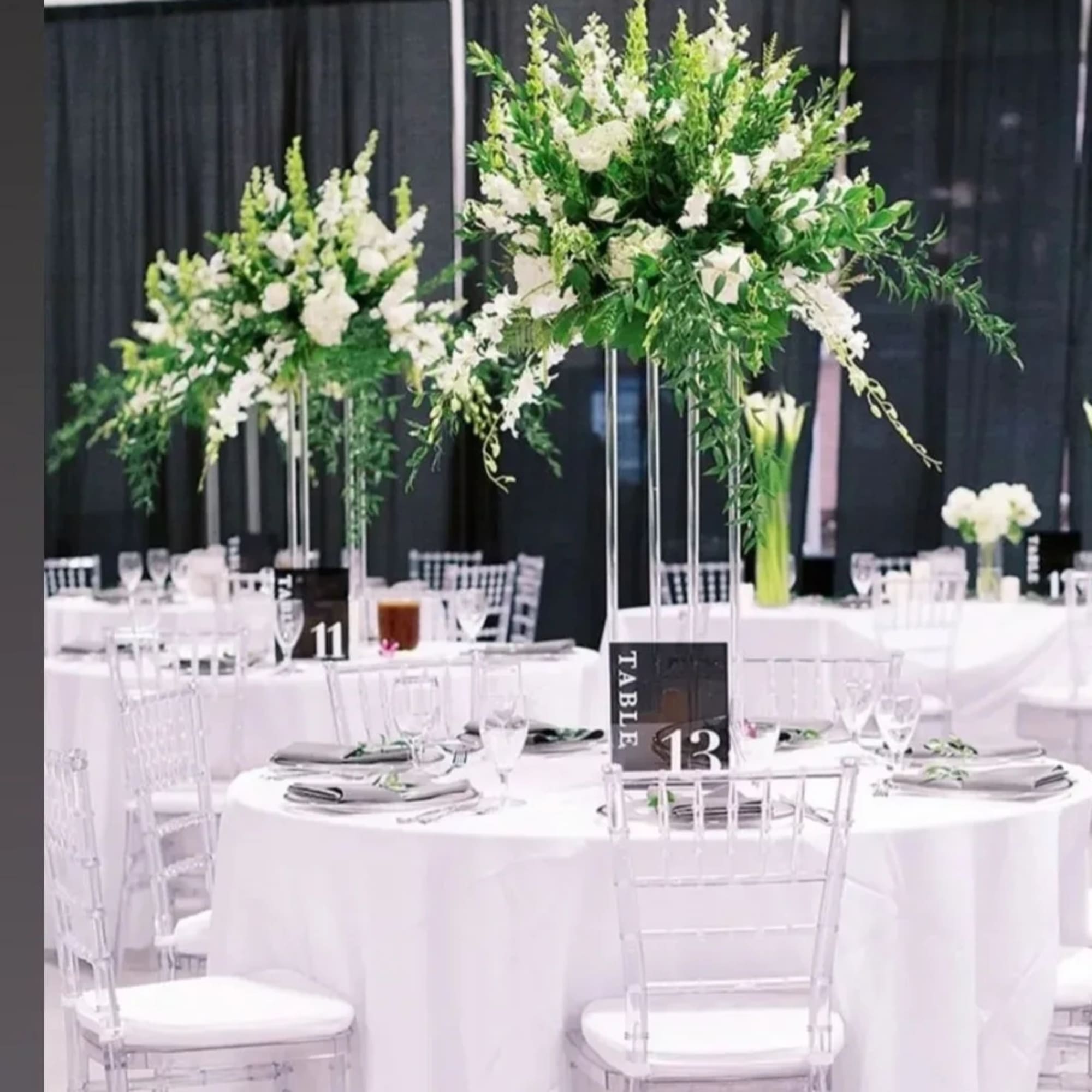 Tall white floral centerpieces on clear stands at round banquet tables