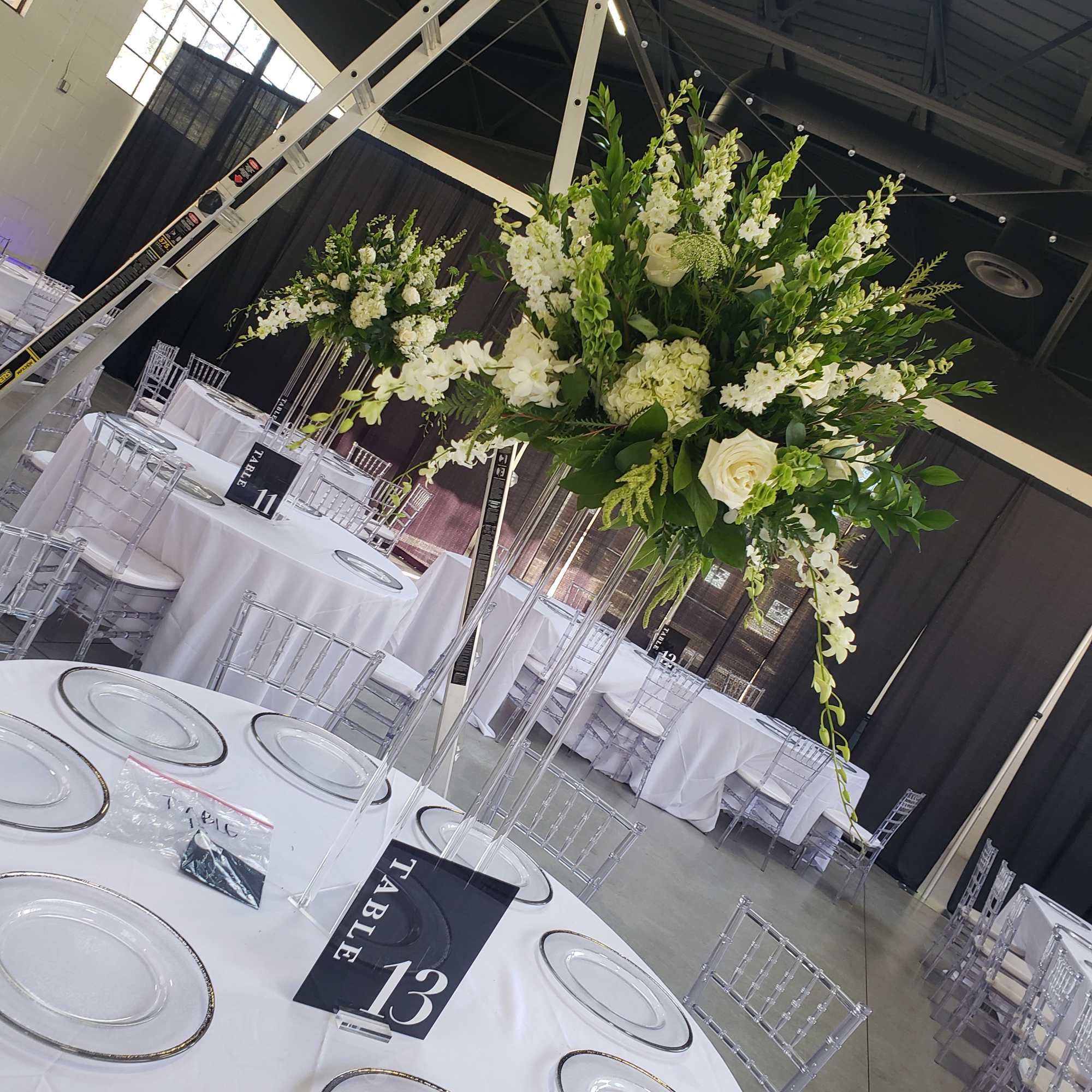 Tall white floral centerpiece on a clear stand at a banquet table
